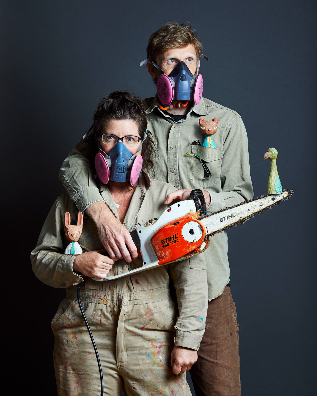 creative artist portrait of AAKSO duo with gas mask and chainsaw and their wooden sculptures