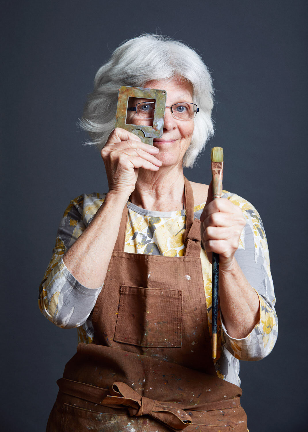beautiful studio portrait of gray haired painter holding paintbrush