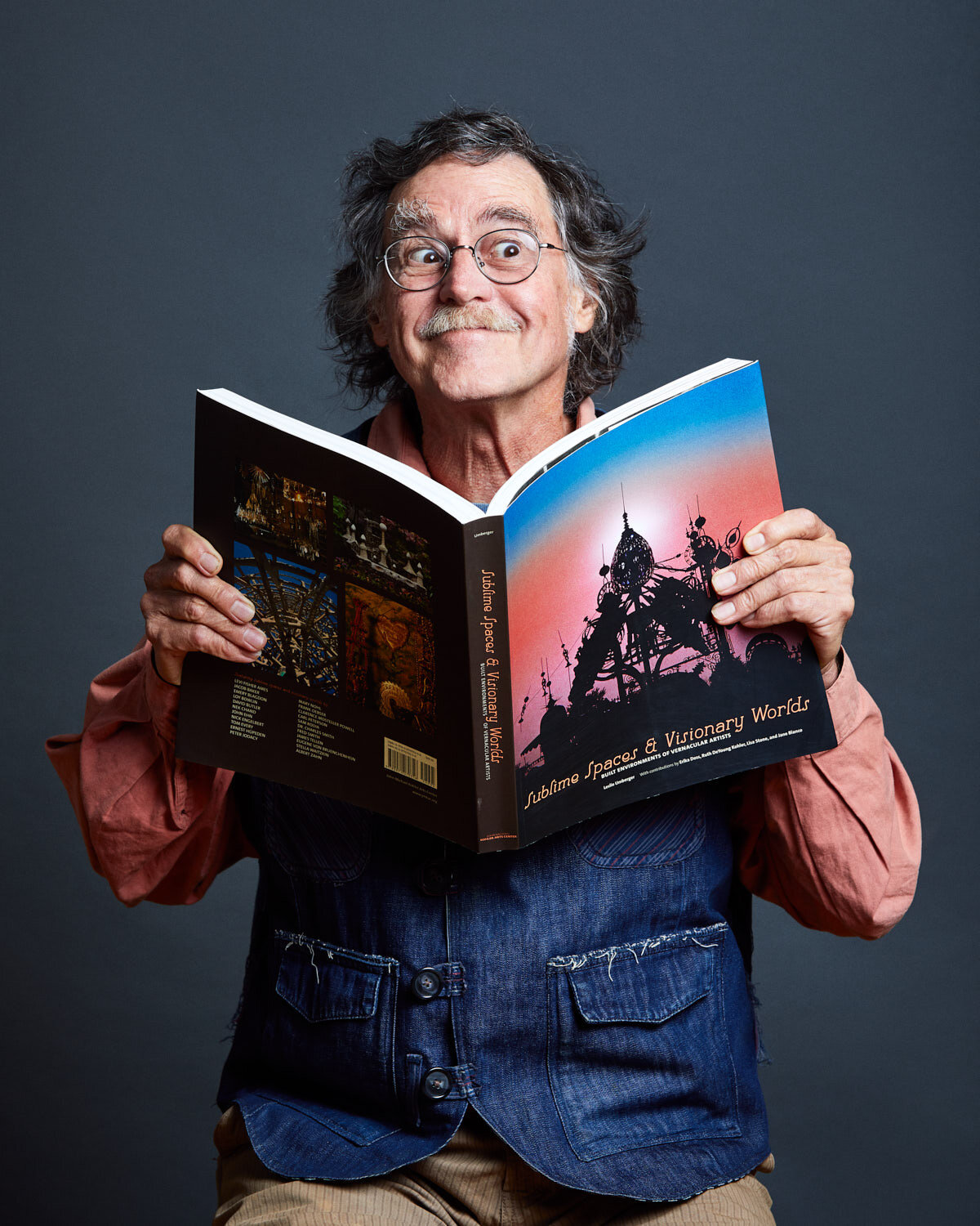 quirky portrait of photographer making silly face and holding his book