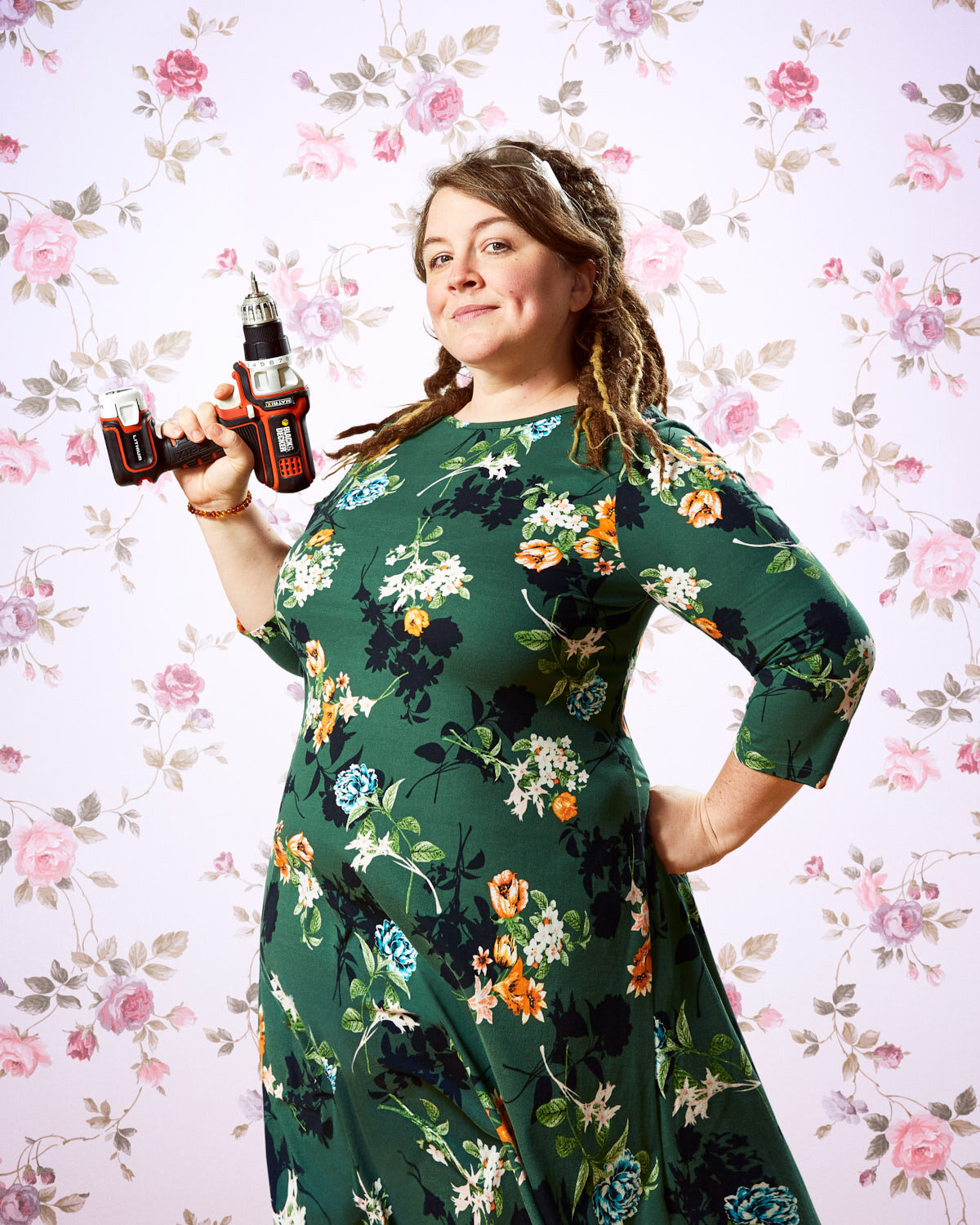mom with dreadlocks, floral dress, and power drill with vintage floral wallpaper by creative portrait photographer Hanna Agar