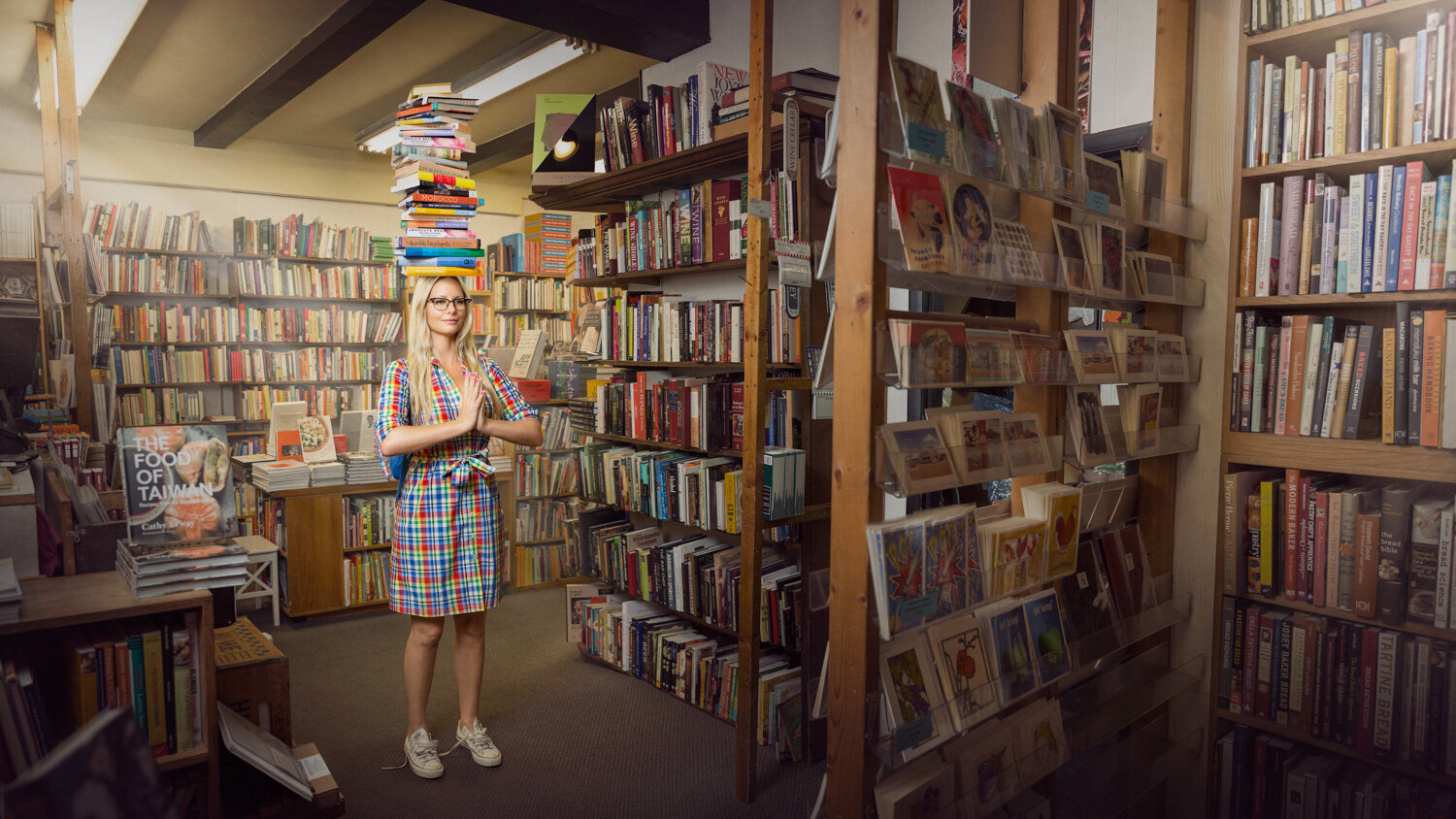 creative portrait of yogi Leila Johnson balancing books on her head in a book store while standing in a yoga pose by creative portrait photographer Hanna Agar