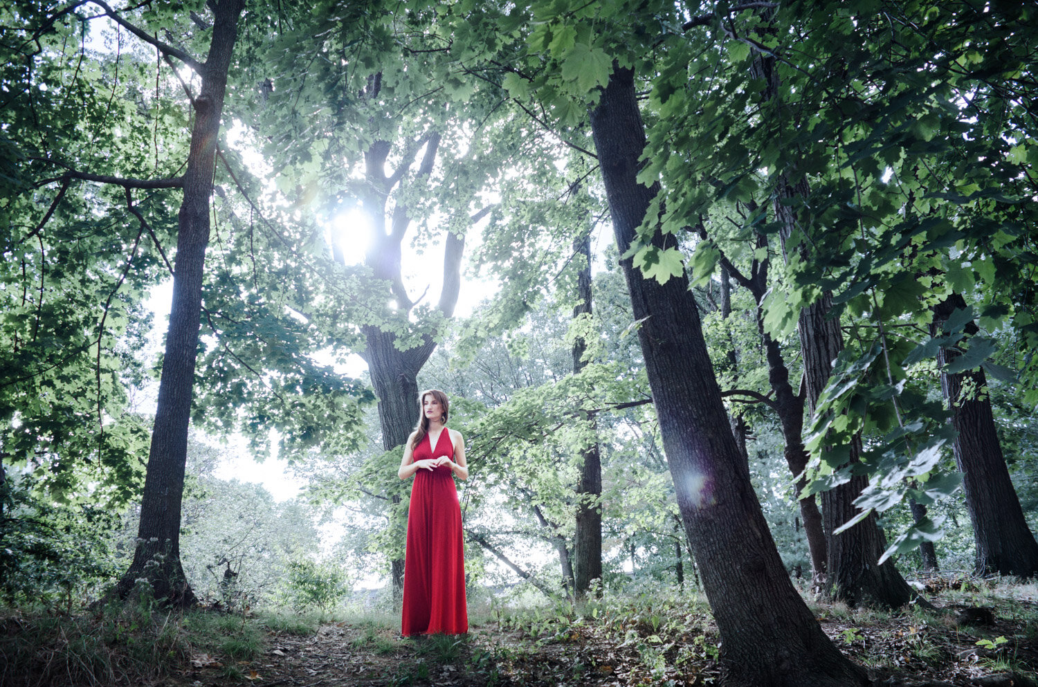 surreal portrait of musician and singer Cora Rose in red dress in eerie woods by creative portrait photographer Hanna Agar