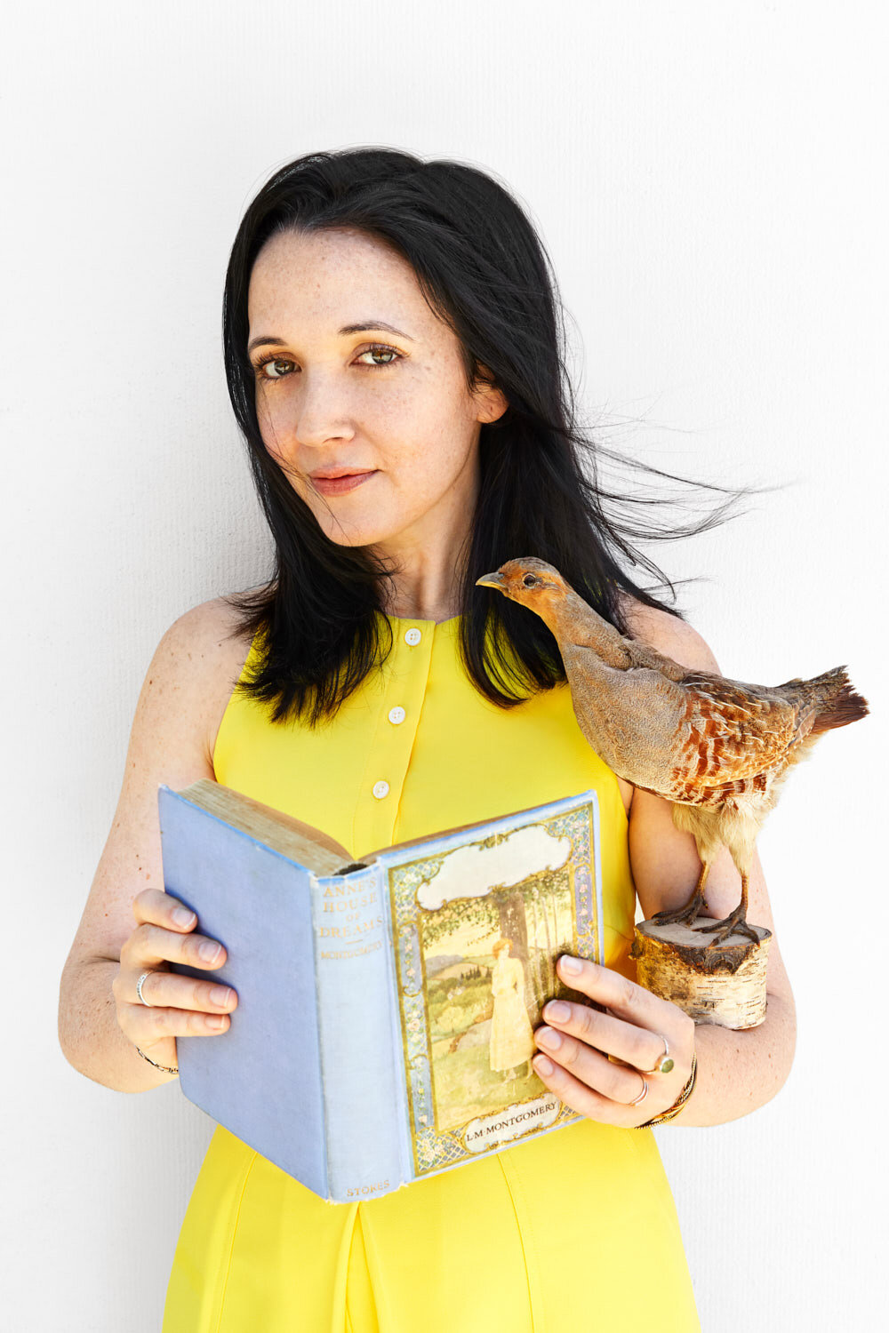 whimsical portrait of writer Jacqueline Raposo holding an old book and a brown bird by personal branding photographer Hanna Agar