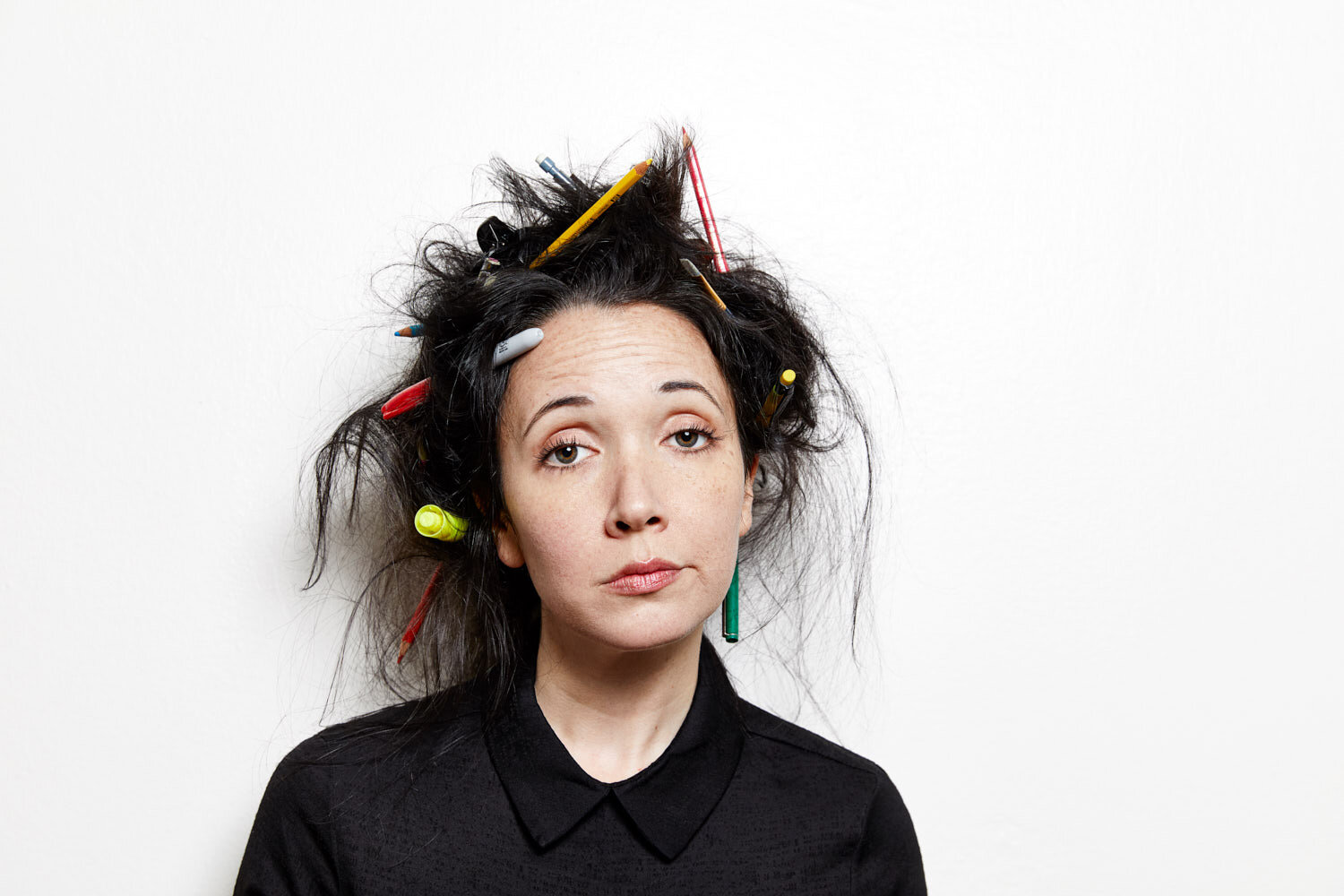 funny portrait of writer Jacqueline Raposo with pens and pencils stuck in her hair and an exhausted expression 