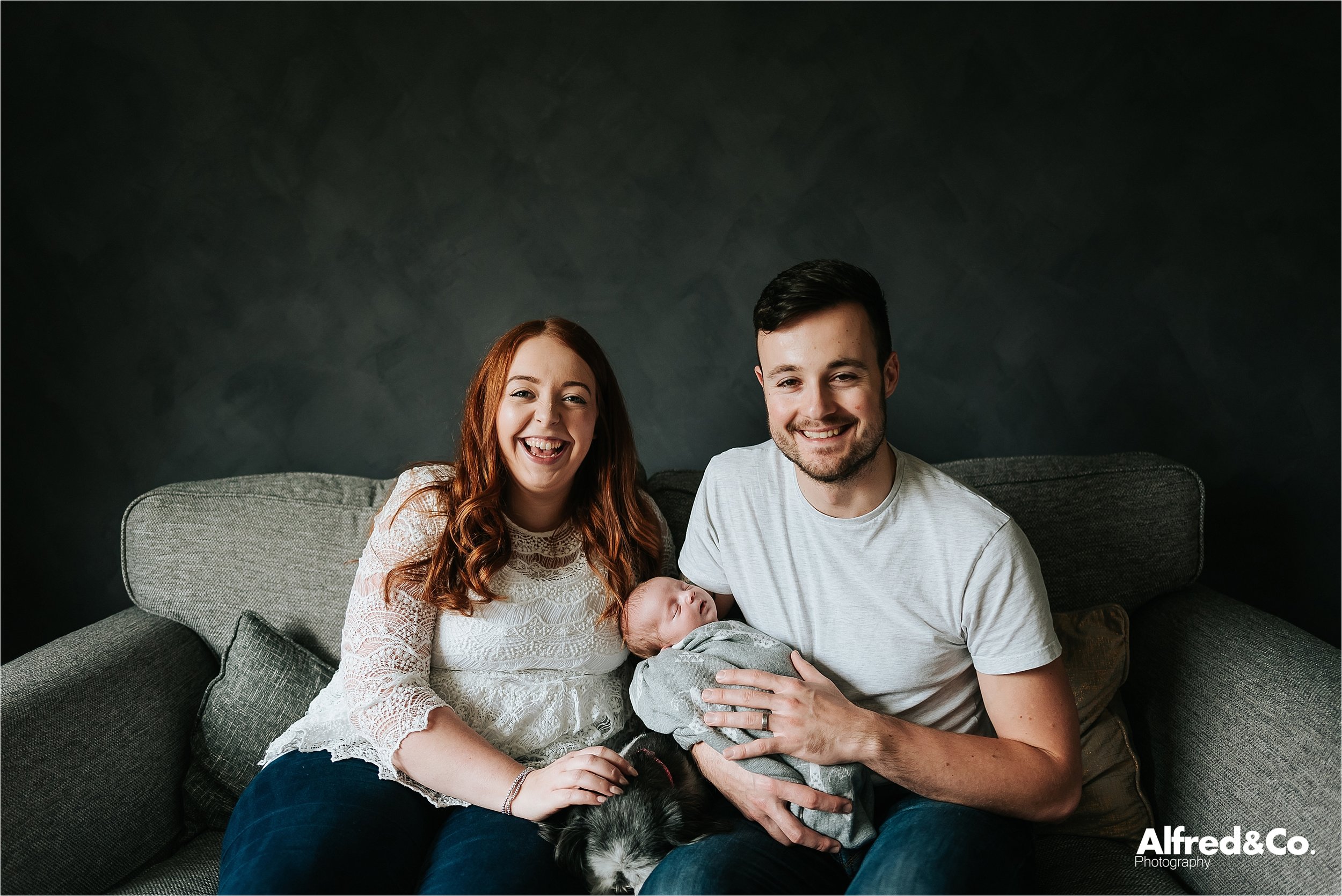 couple pose on couch with baby 