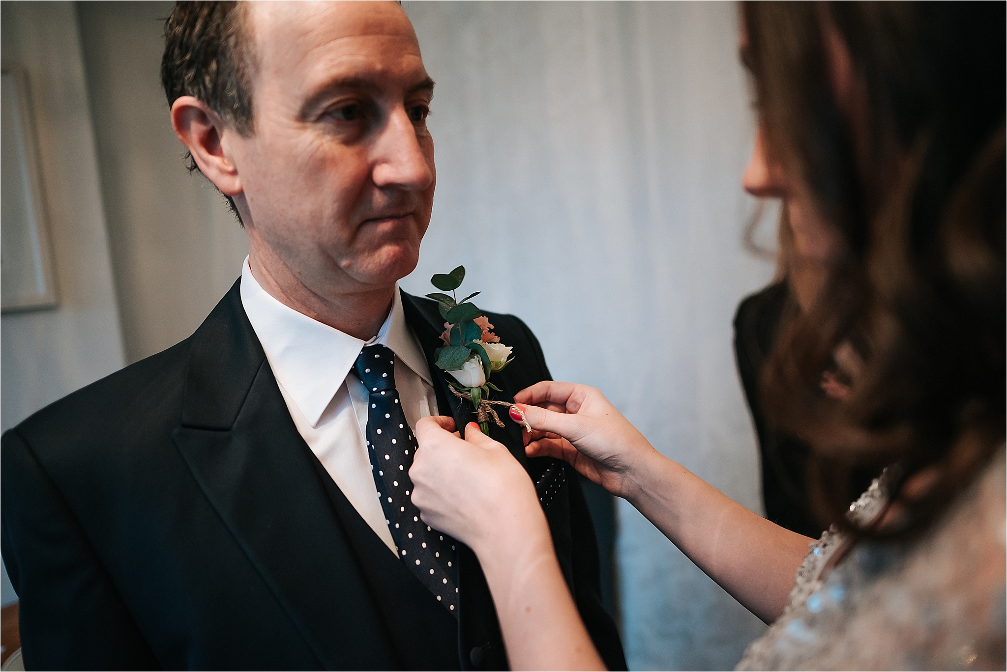 bridesmaid putting a flower on to dad at wedding