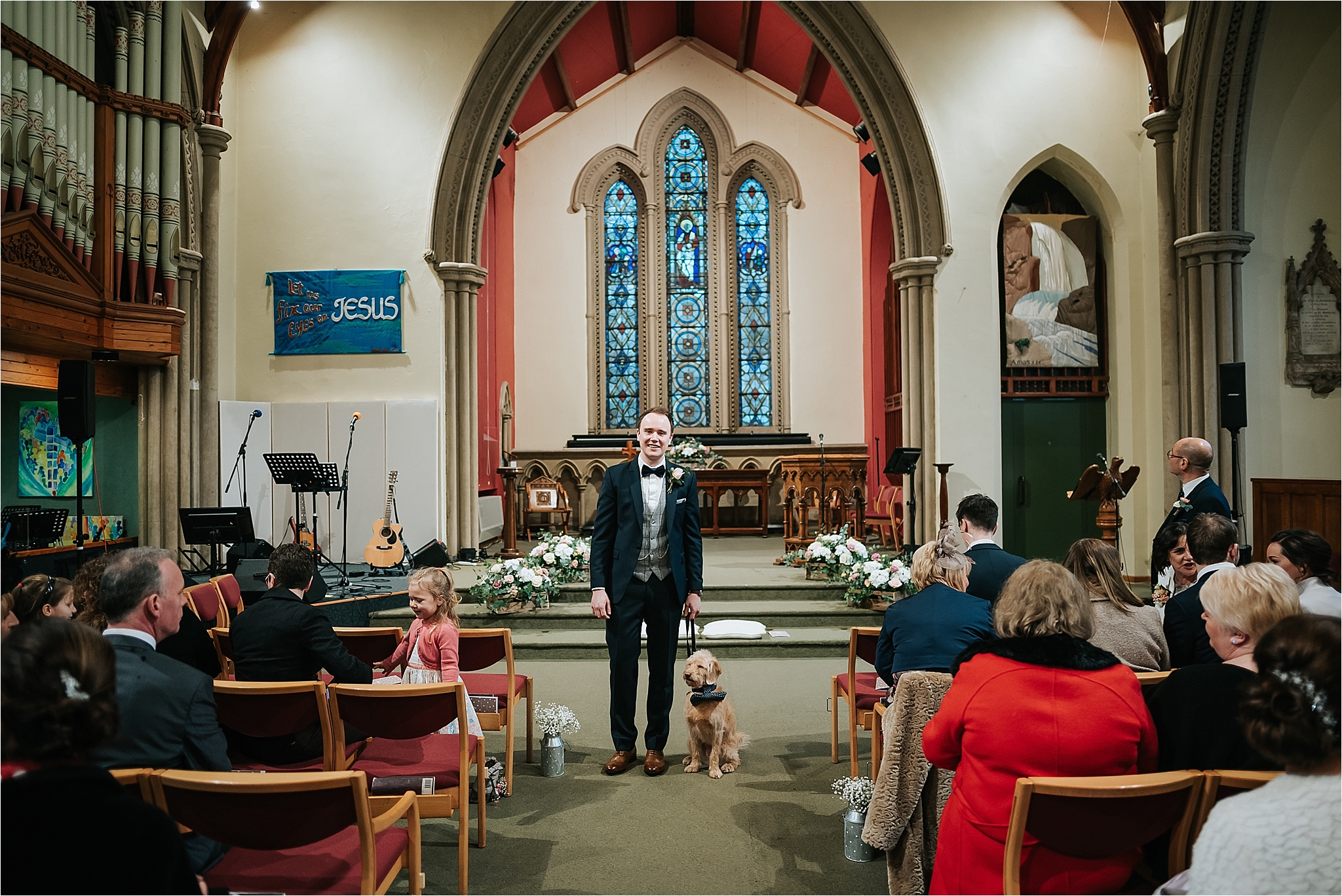 groom and dog at the top of the aisle in church for wedding