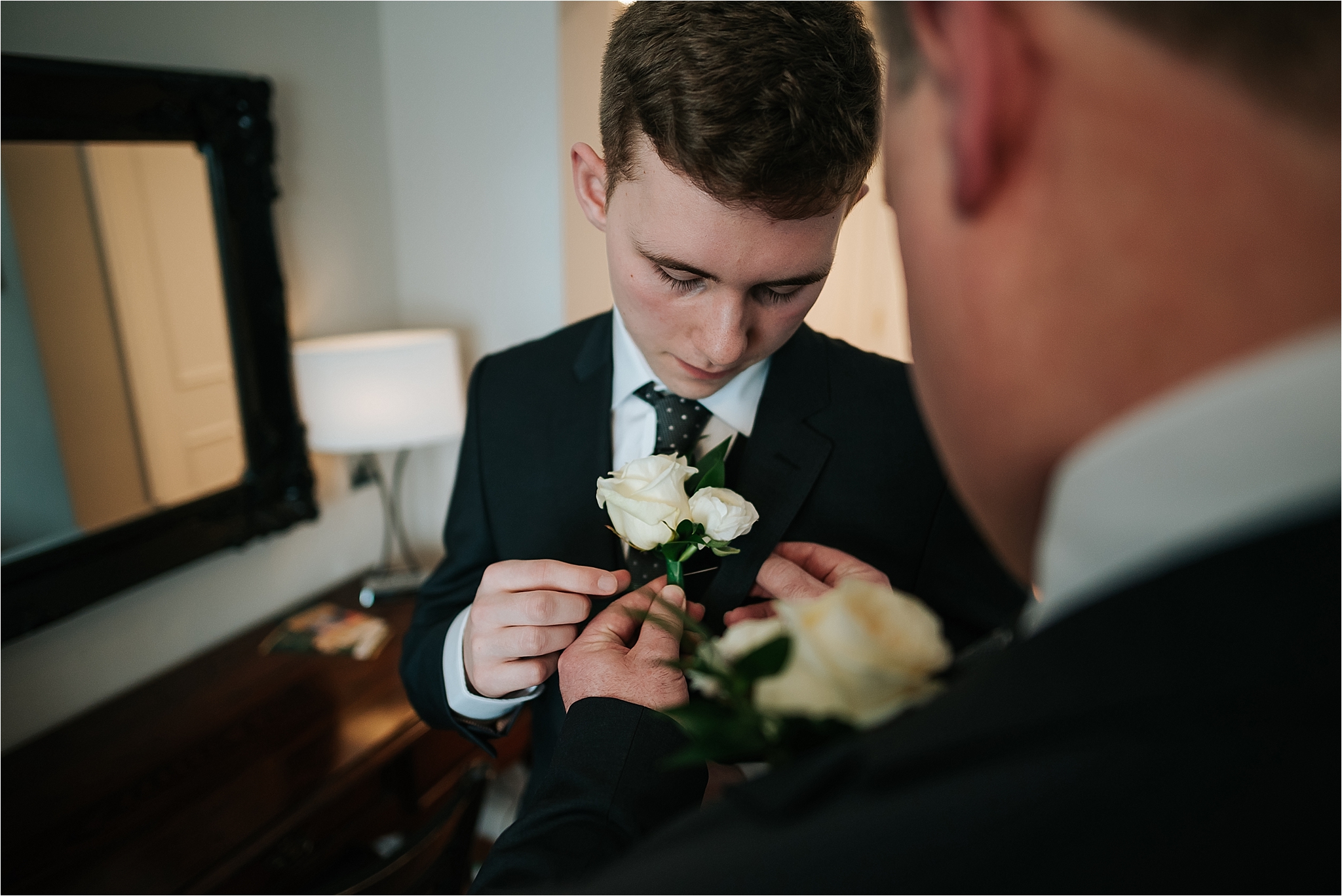 dad putting buttonhole on his son at wedding 