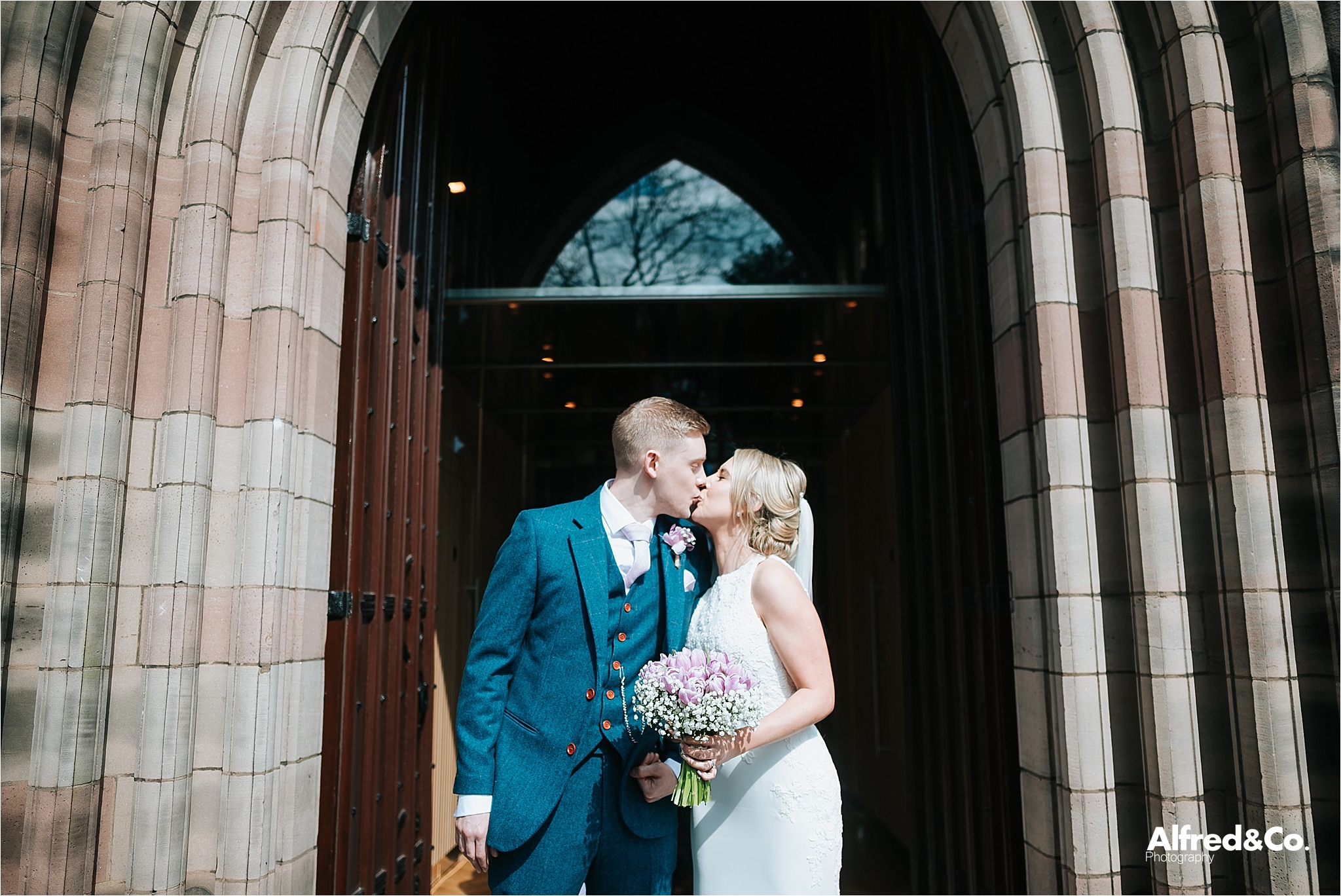 bride and groom kiss outside mossley hill church
