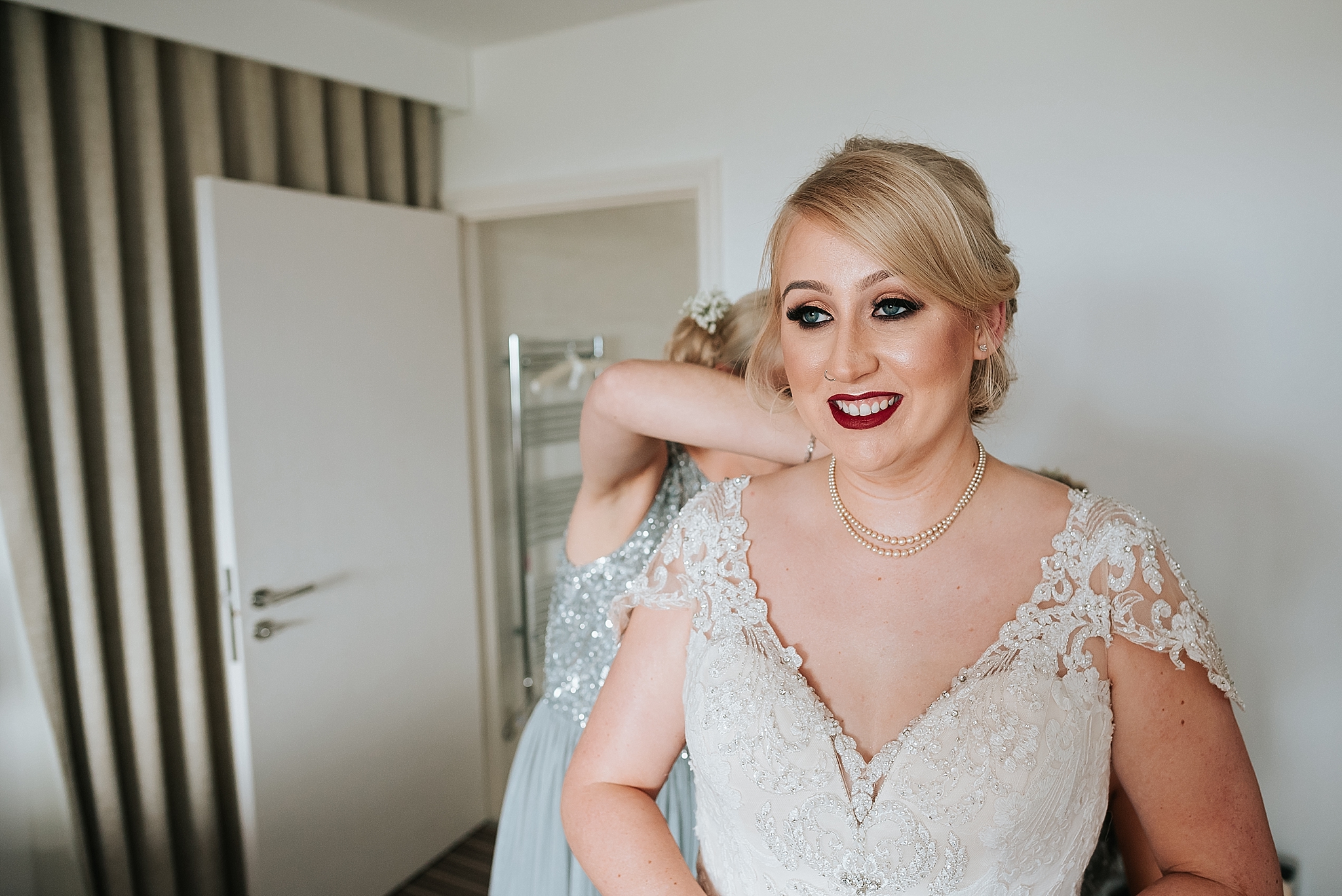 bride getting wedding dress on before wedding