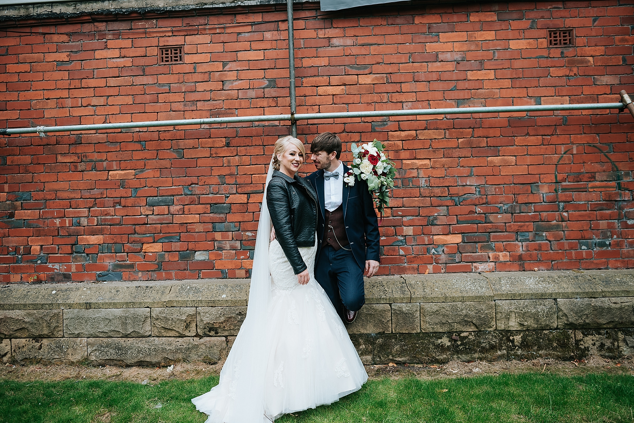 cool bride and groom in front of red brick in ashton park, st annes