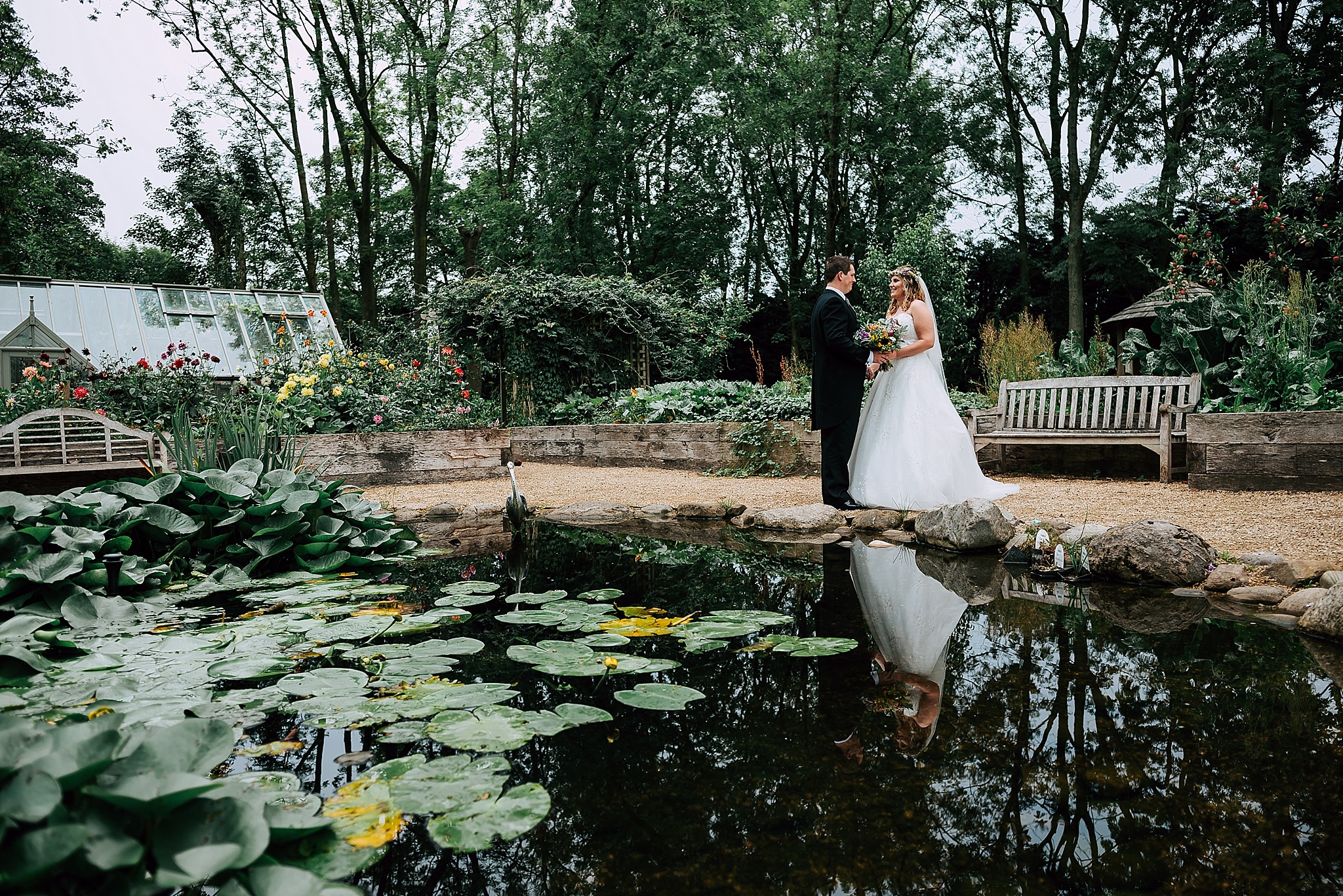 bride and groom next to pond in the village garden