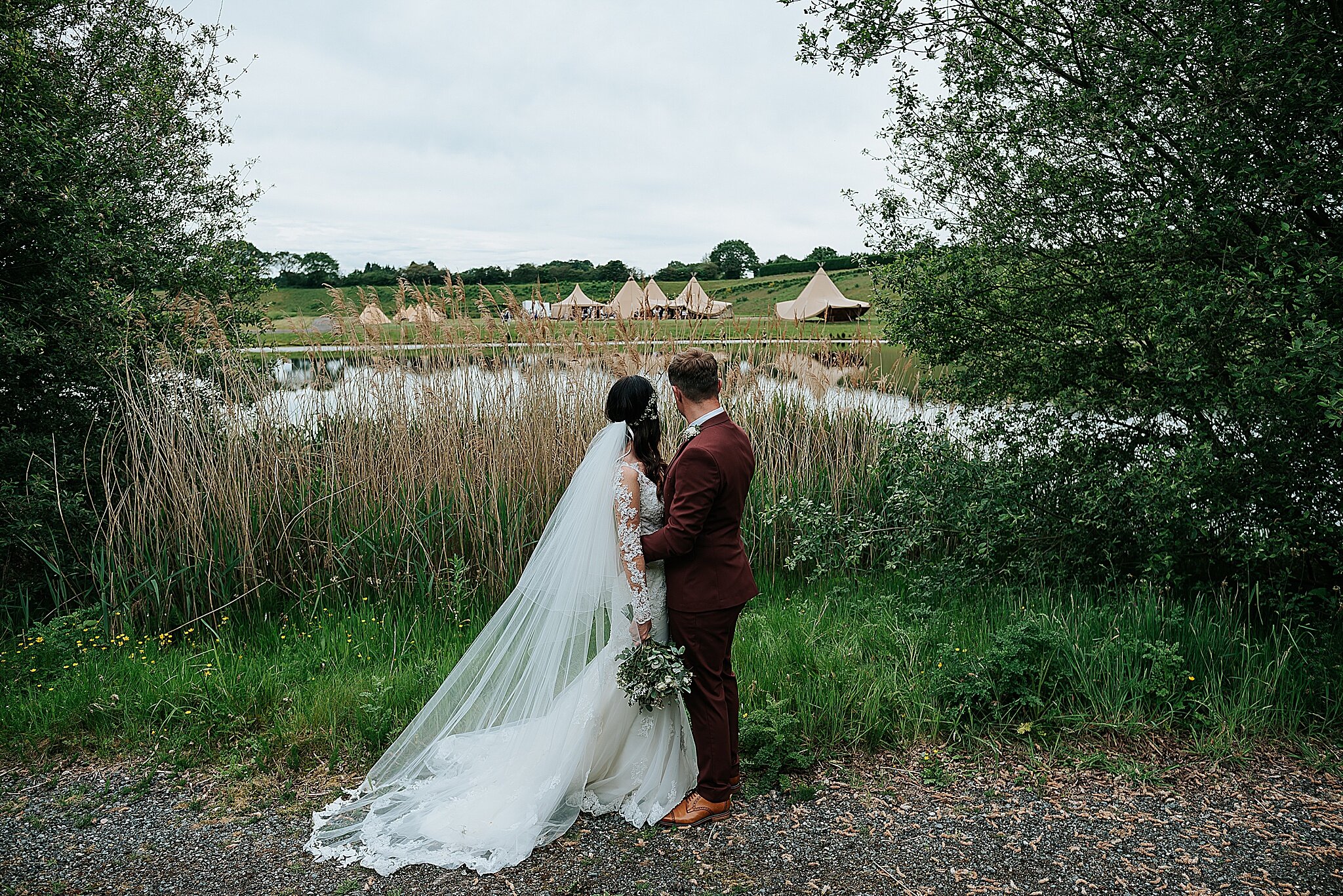 bride and groom looking out over cherry orchard lake in delamere