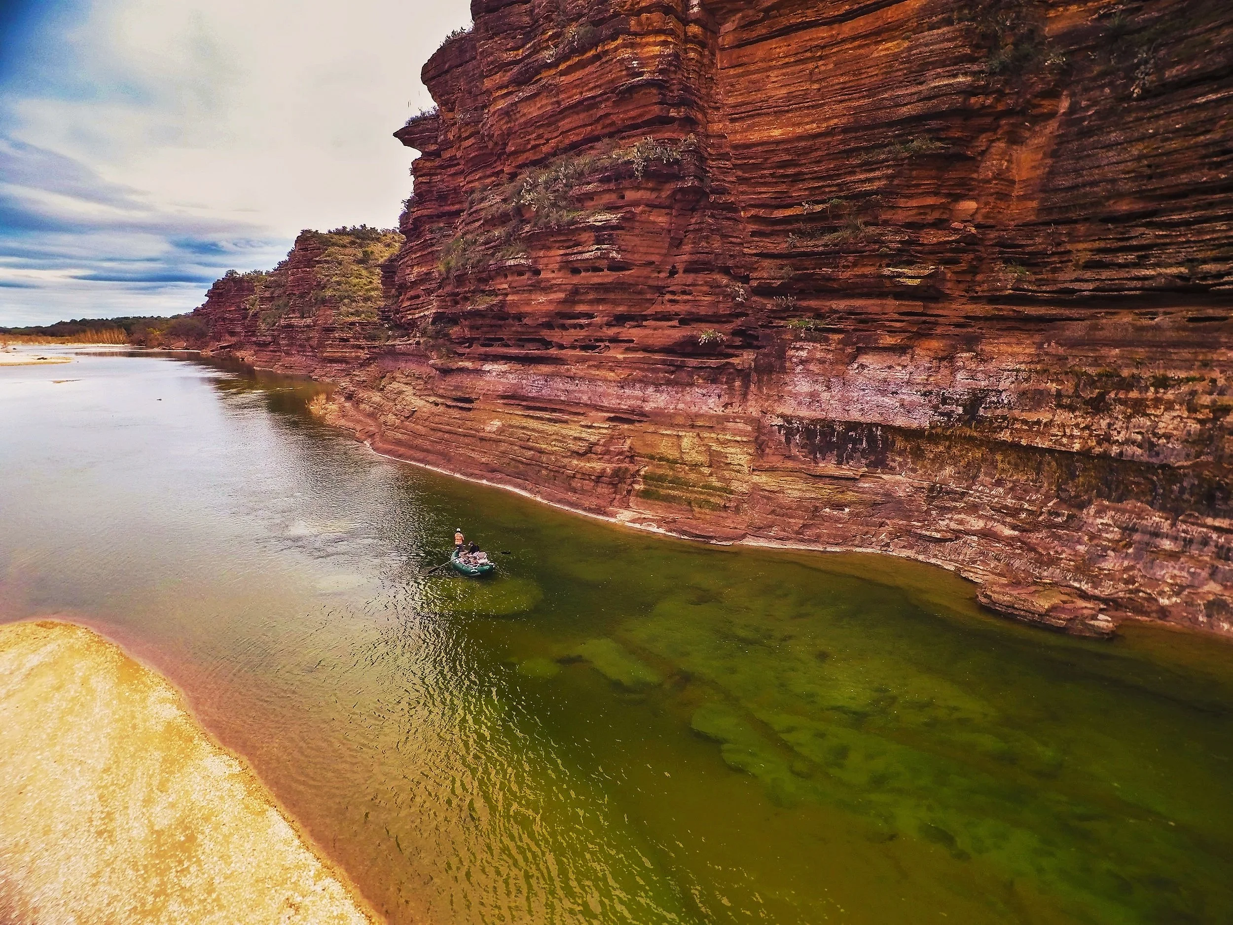 Anglers floating beneath limestone cliffs on a Central Texas river