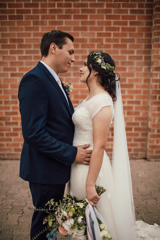 bride and groom in front of brick wall