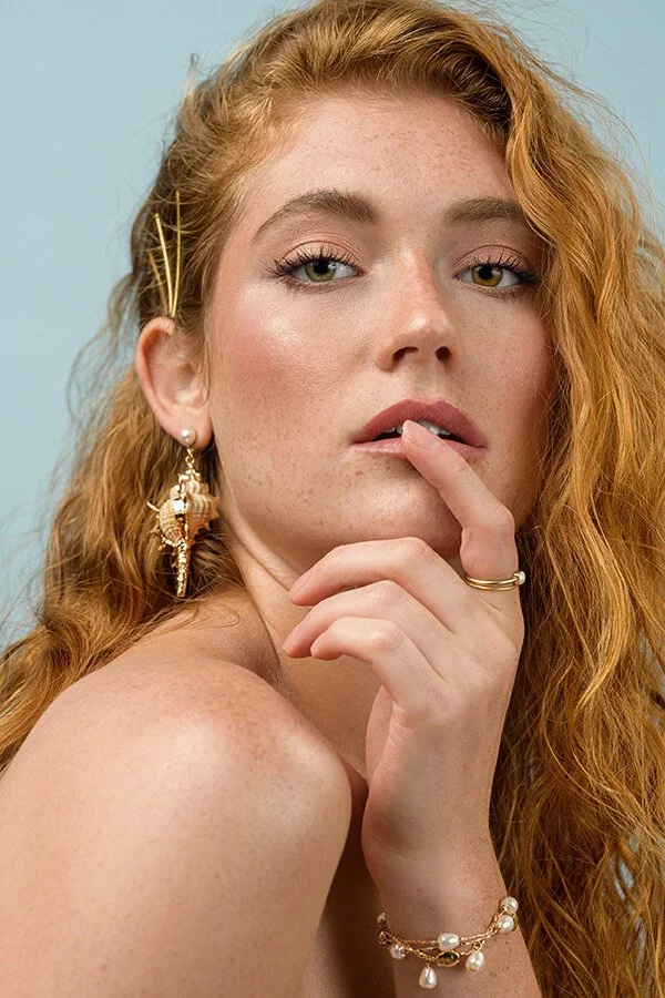 Woman with finger on lip and seashell earrings photographed by Philadelphia Photographer Justus Henry