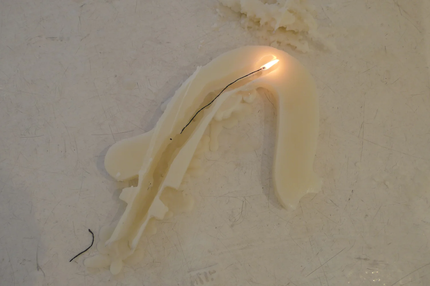 Memory is a Hussy . Beeswax, wicks, weights, and rope. The chandelier arm continues to burn on the floor. 2011.