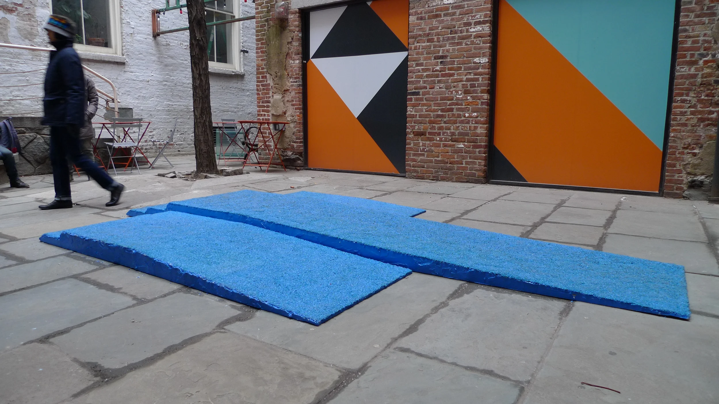   Champion Takes All , Installation view in Canon's Walk courtyard in the South Street Seaport, NYC. Visitors loitered on the podium and walked over it as they traversed the courtyard. Three piece podium, 12.5' long x 90" wide x 6" tall. Rubber granu