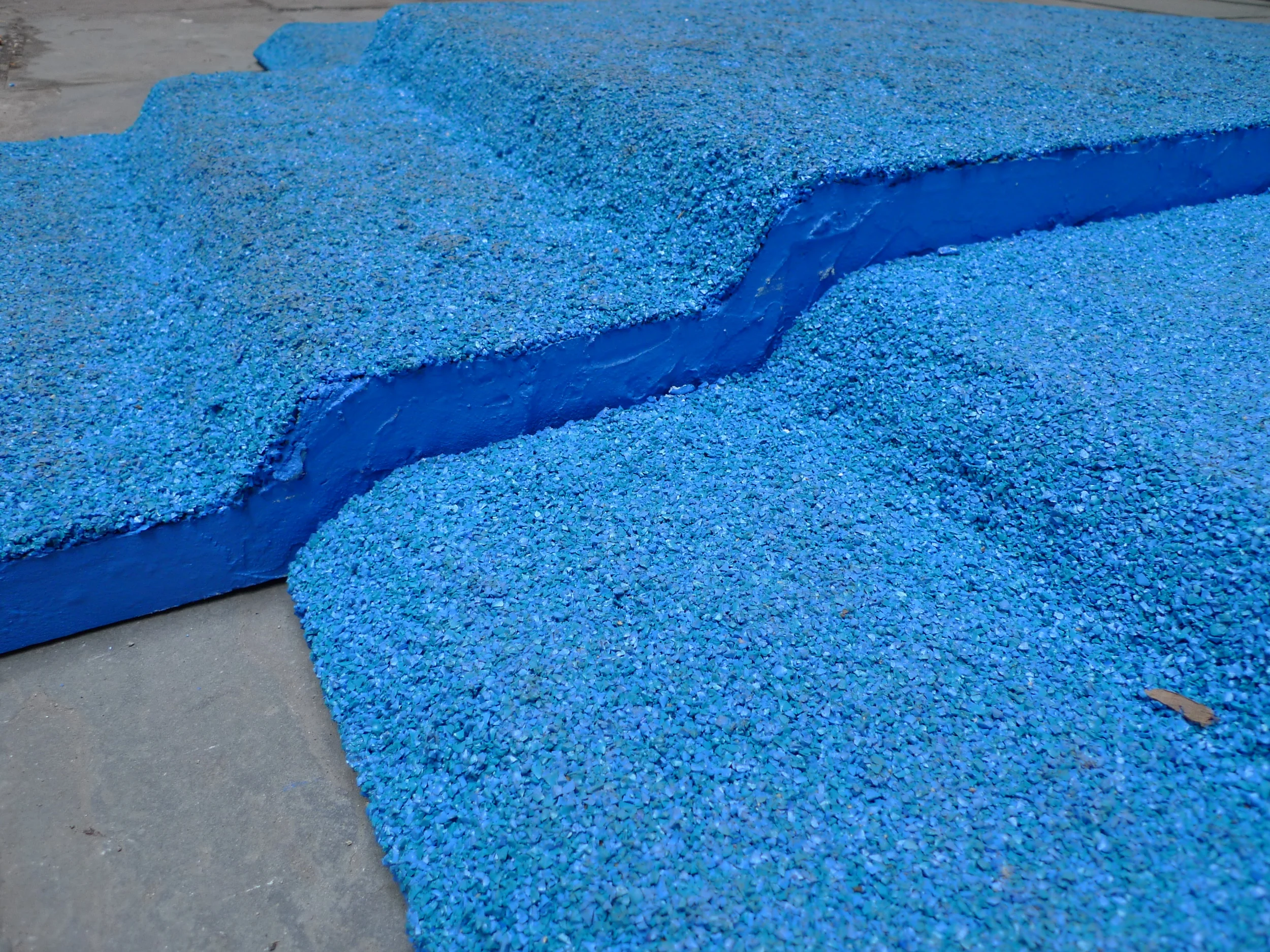   Champion Takes All , Installation view in Canon's Walk courtyard in the South Street Seaport, NYC. Visitors loitered on the podium and walked over it as they traversed the courtyard. Three piece podium, 12.5' long x 90" wide x 6" tall. Rubber granu