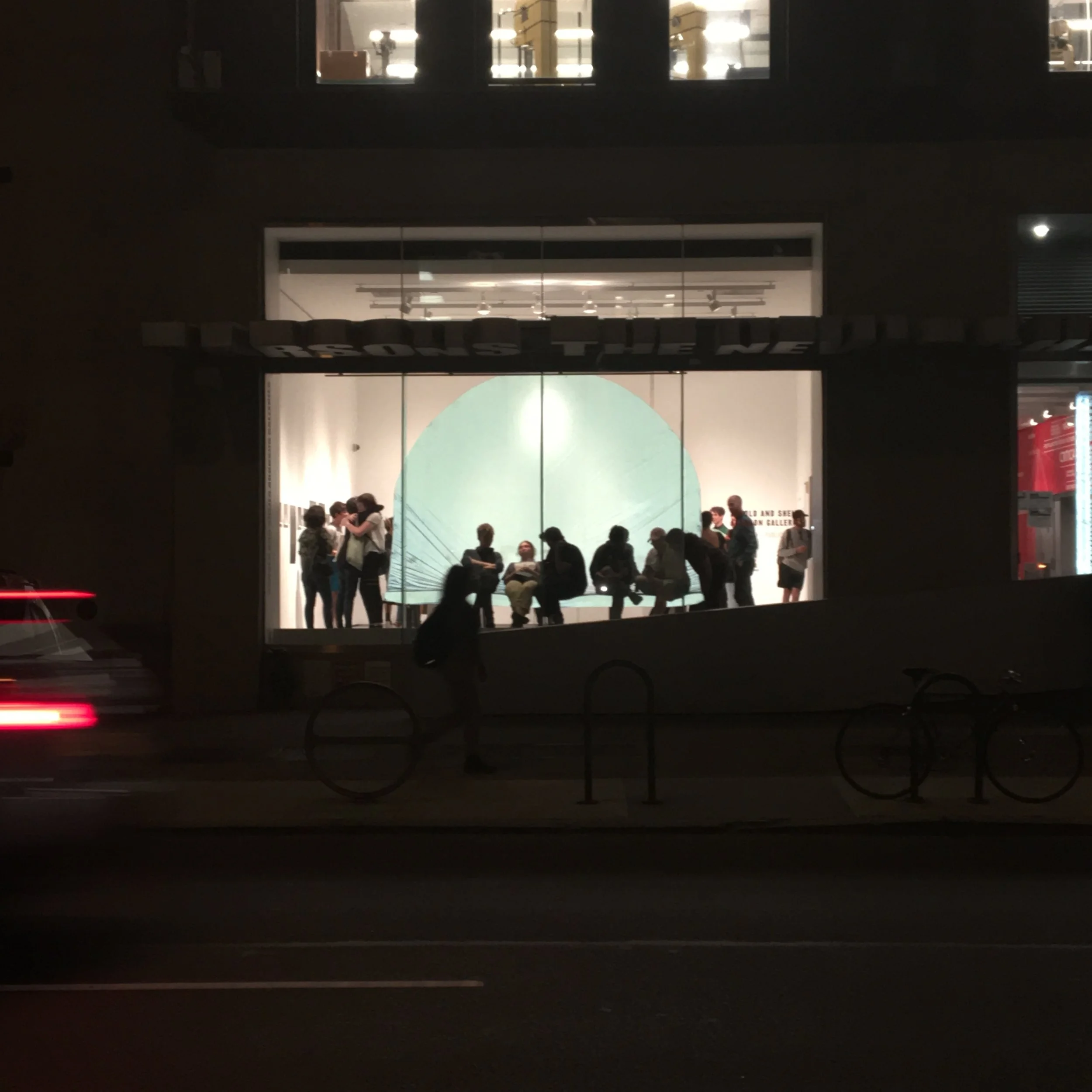  Invert &nbsp;at night. The light from passing vehicles bounces off the sculpture's reflective slip cover and silhouettes the people sitting on it. 