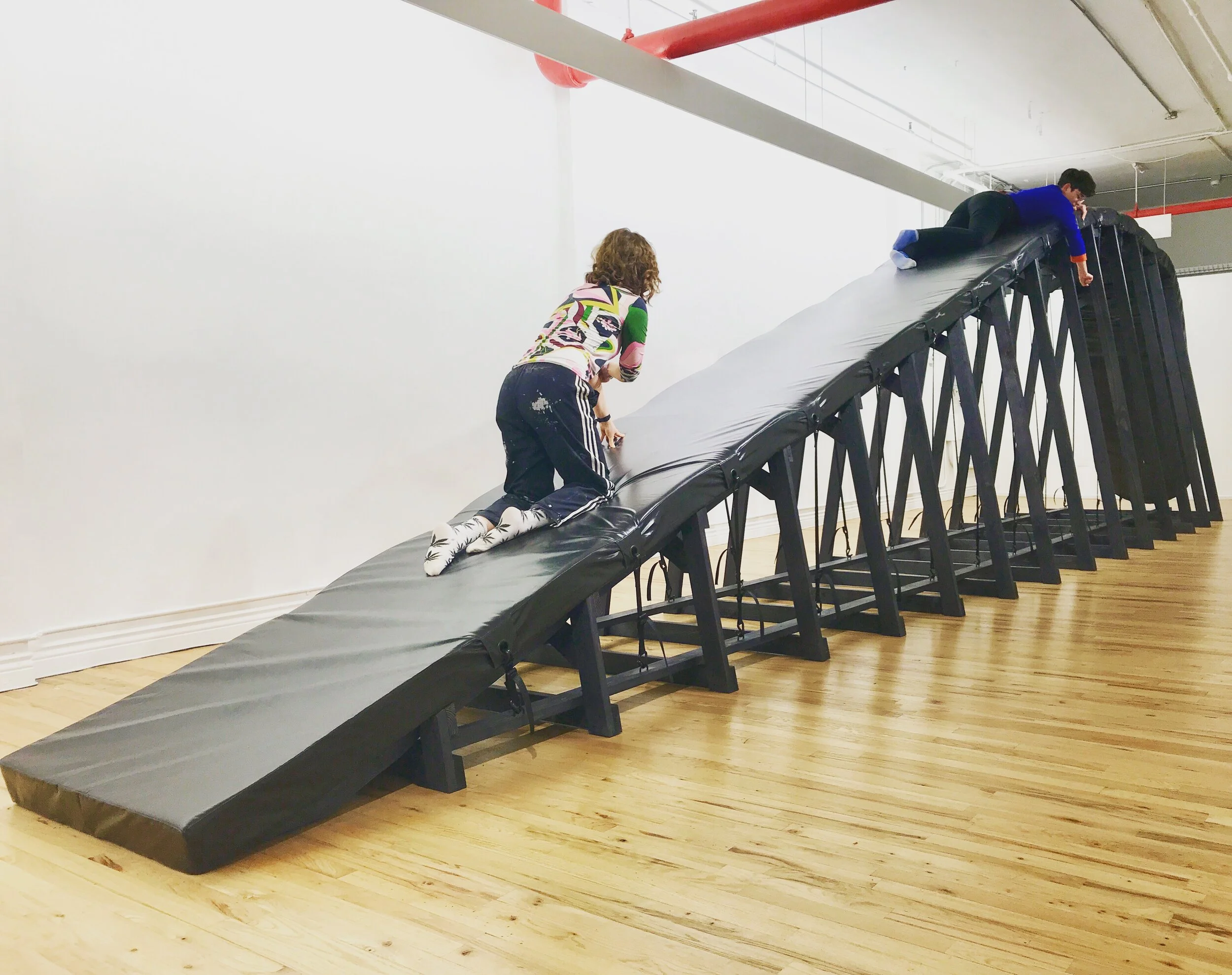   Reenactment: Spit You Out , 2018. Wood recycled from old projects, dye, wax, webbing, hardware, rubber, webbing, upholstery foam, vinyl. 40 ft long x 6 ft at widest x 8.5 ft at tallest. Installation view at Hercules Project Space, NYC. 