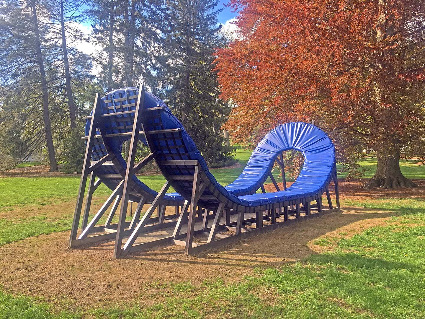 Double Grave , 2019-20. Wood reclaimed from old projects, steel, dye, varnish, webbing, rubberized hardware, foam, vinyl. 28 ft long x 12 ft wide x 10 ft tall. Installation view at DeCordova Sculpture Park and Museum, Boston, MA, as a part of the 2019 DeCordova Biennial curated by Sarah Montross.