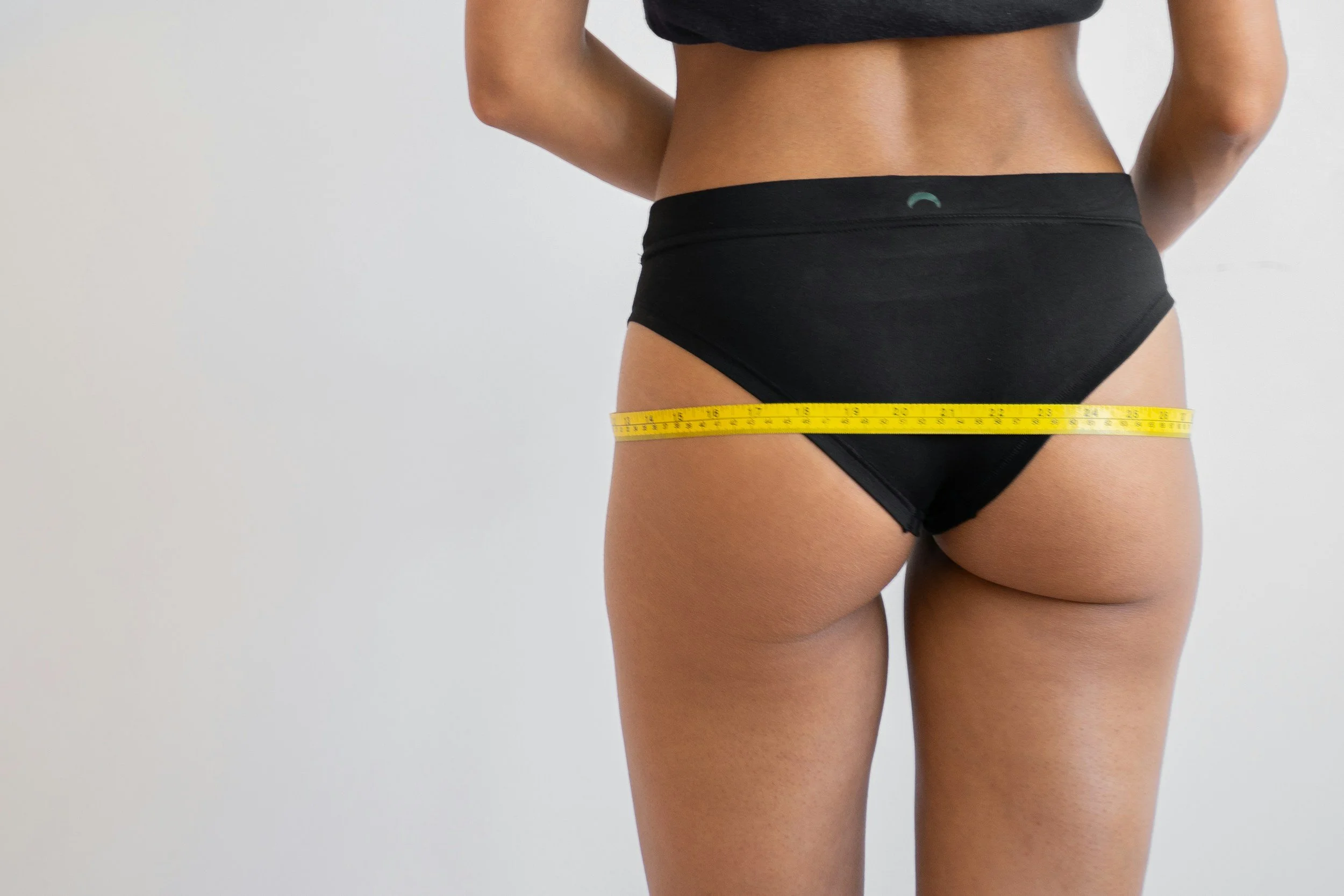 women in a black brief with a tape measure