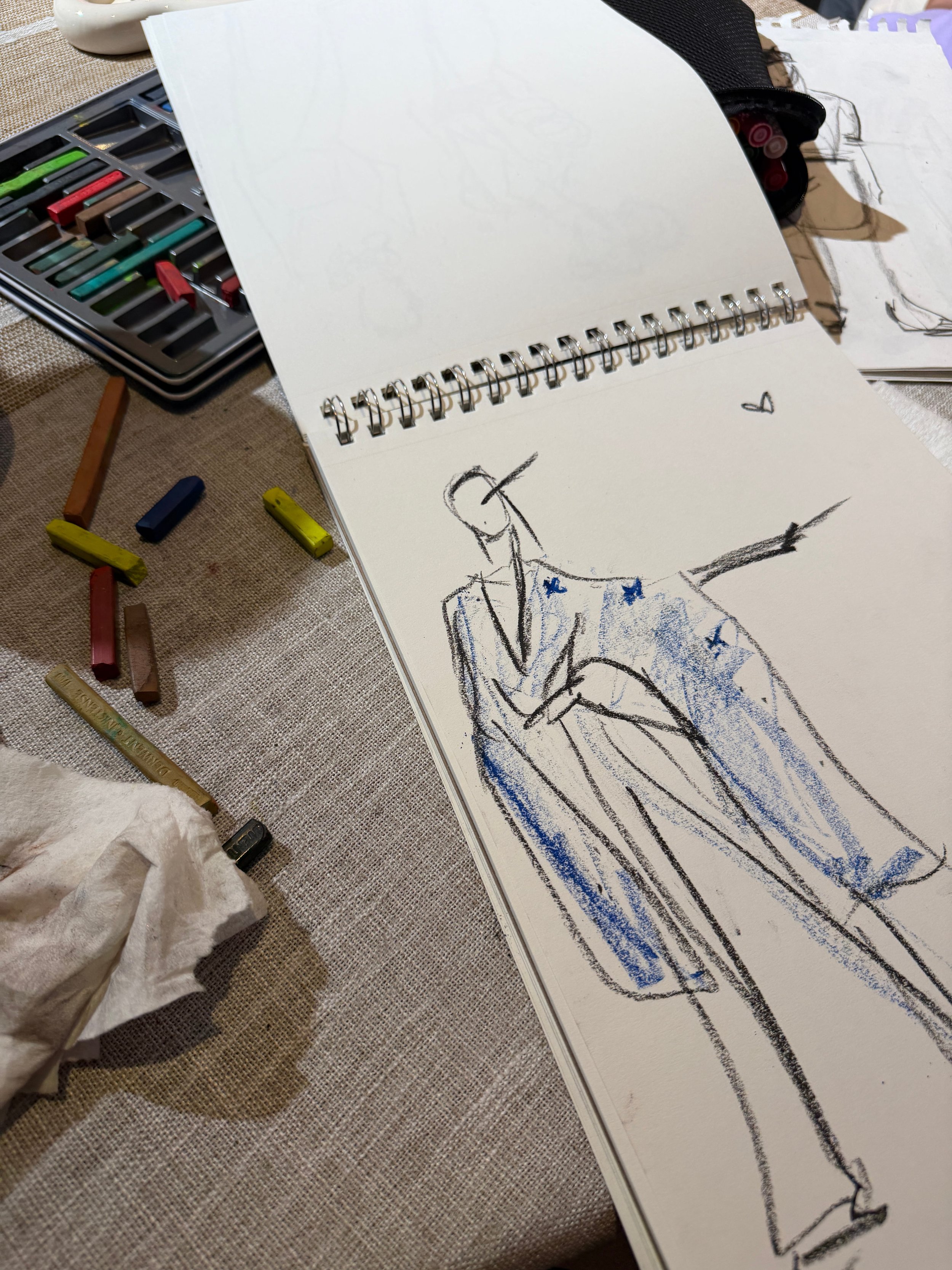 Fashion illustration sketchbook with watercolor and ink drawing in progress.