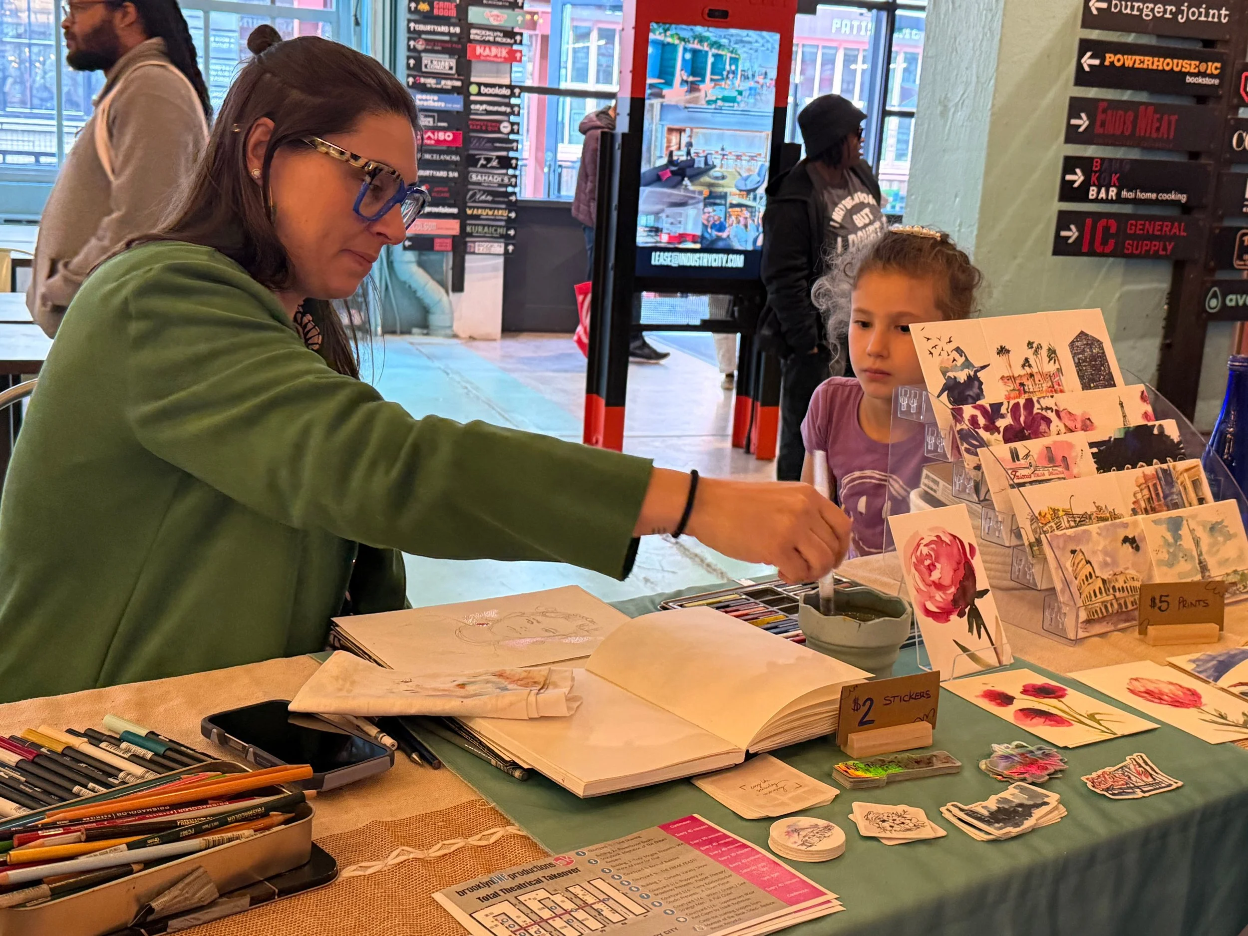 Danielle drawing portraits of children at a live drawing event in Industry City