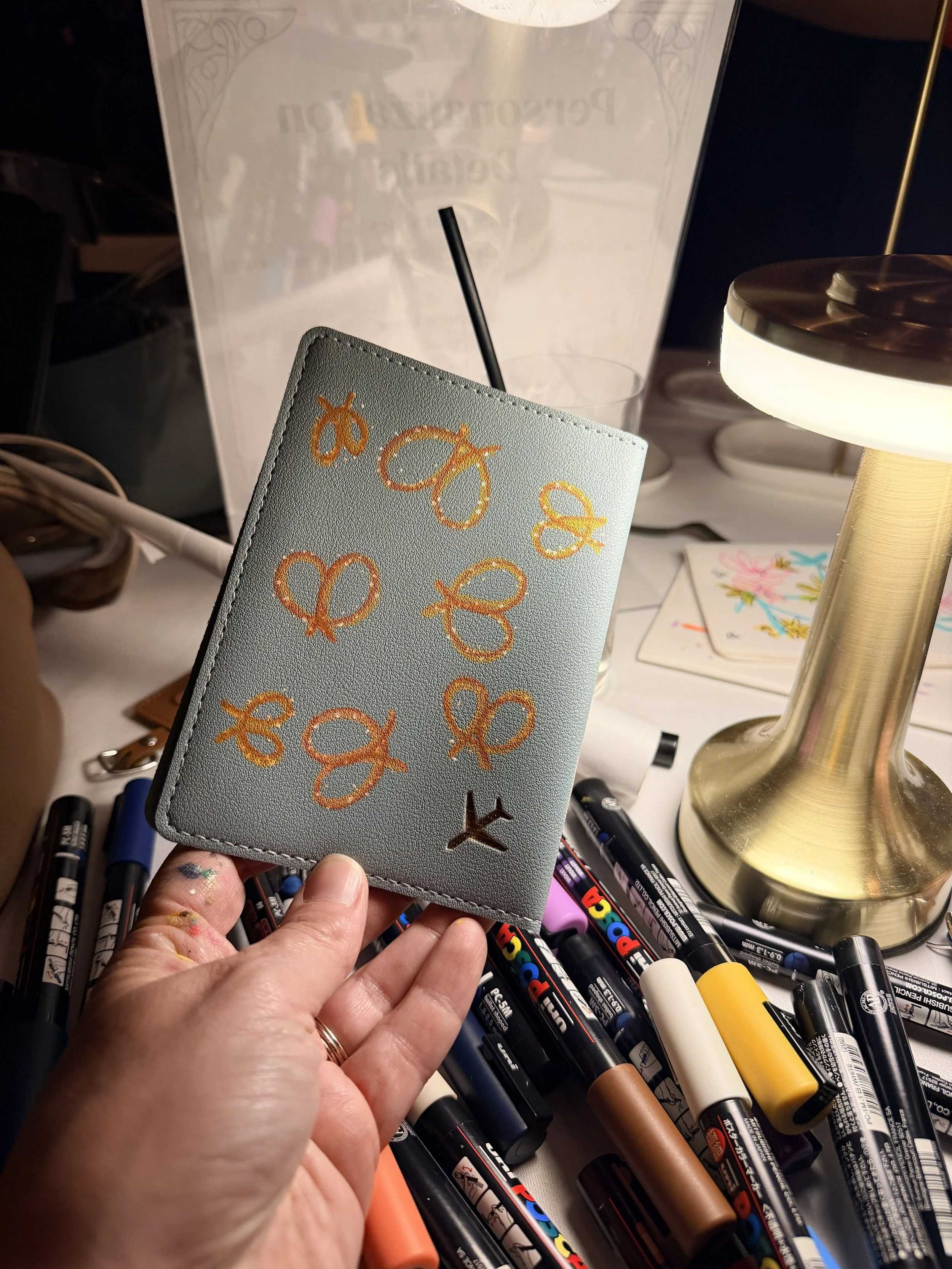Custom hand-painted mint passport holder covered in pretzel motifs — live personalization for The Young Angels Gala by Danielle Rose Fisher NYC