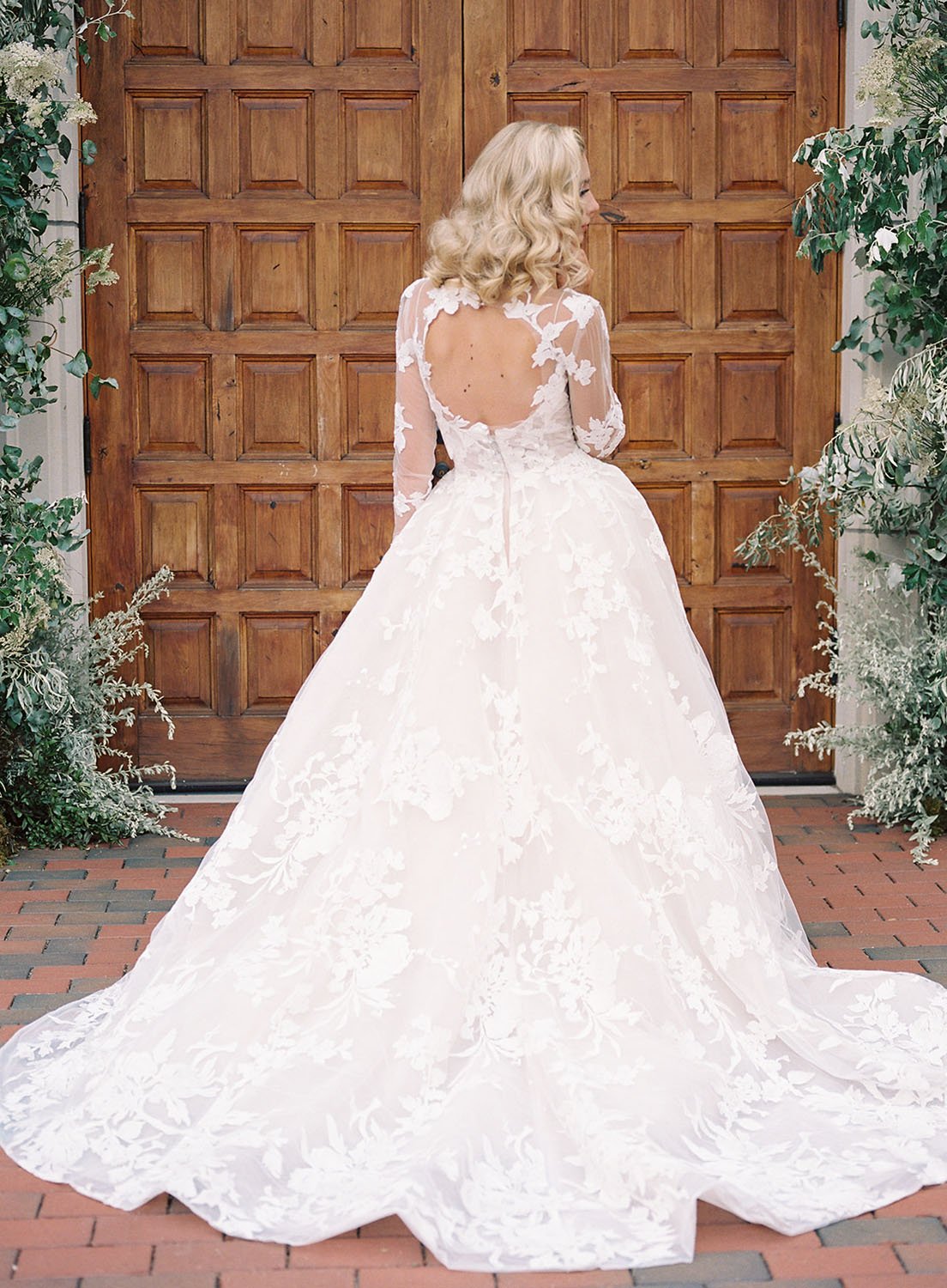  a bride wearing 'Maeve' by Monique Lhuillier wedding dress standing in front of regal double doors at a Villa in Wisconsin for a spring wedding 