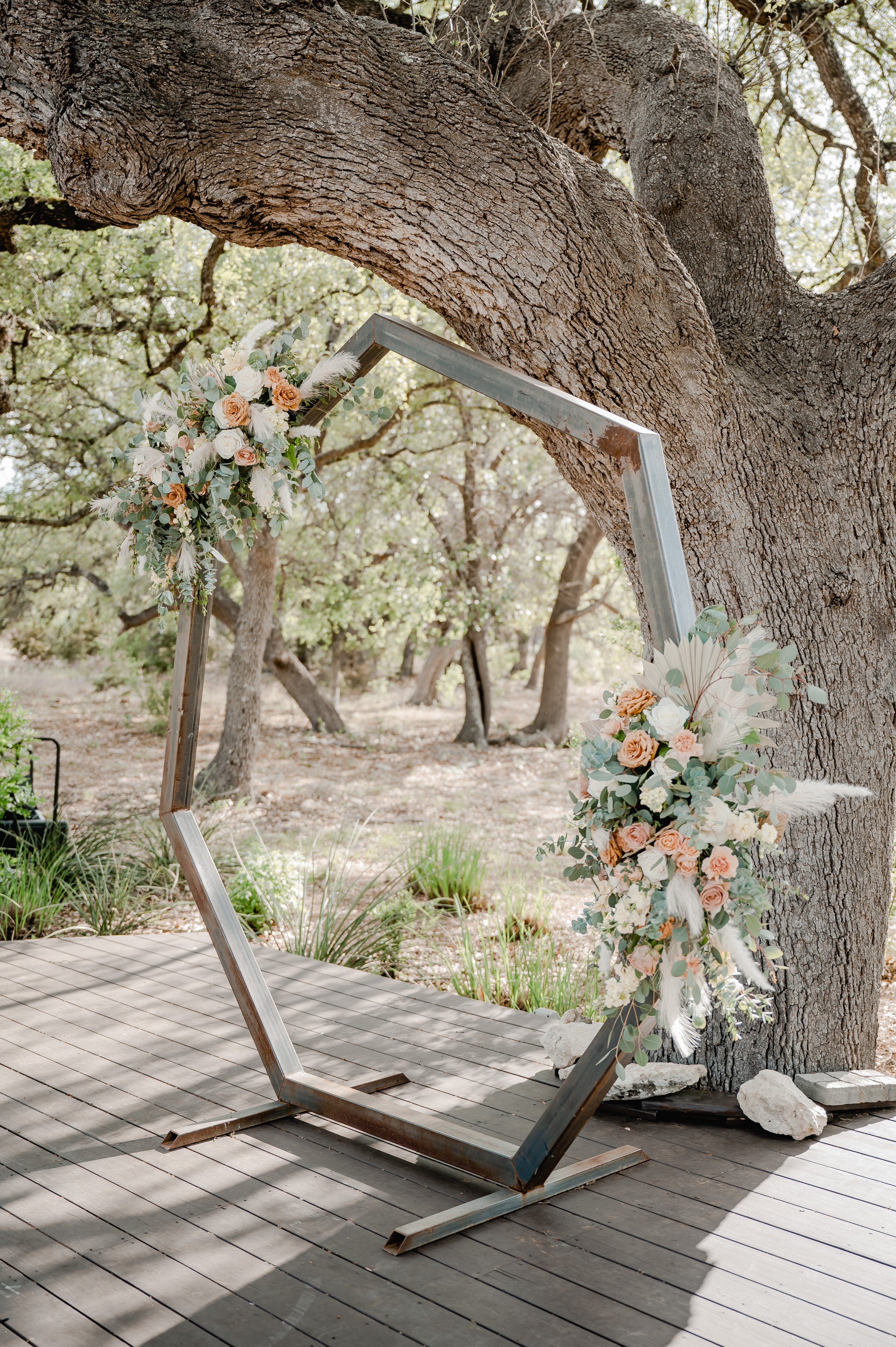 a modern wood arch for the wedding ceremony with blush and green florals.