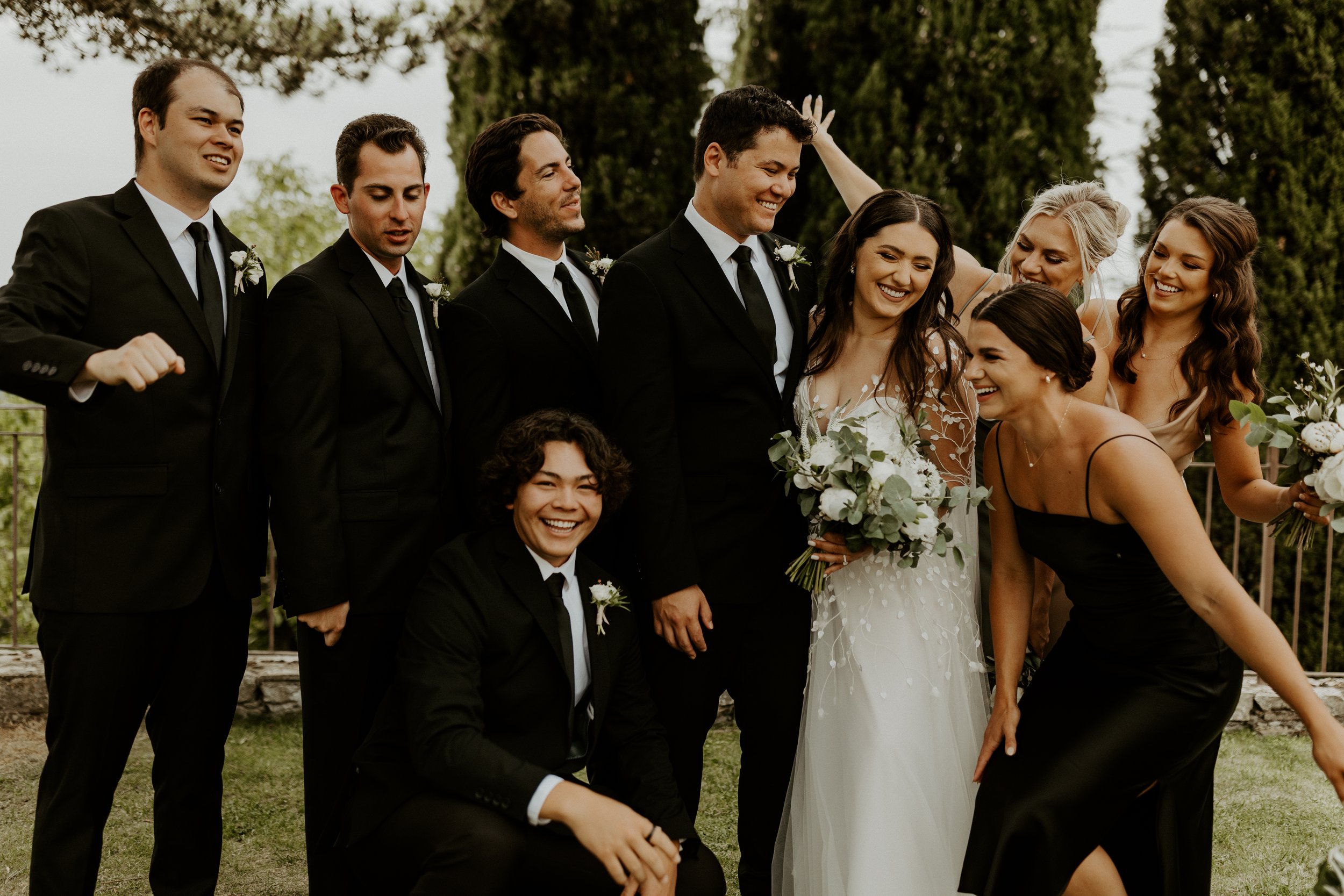 a chic and fun bridal party featuring classic black suits and silk bridesmaids dresses