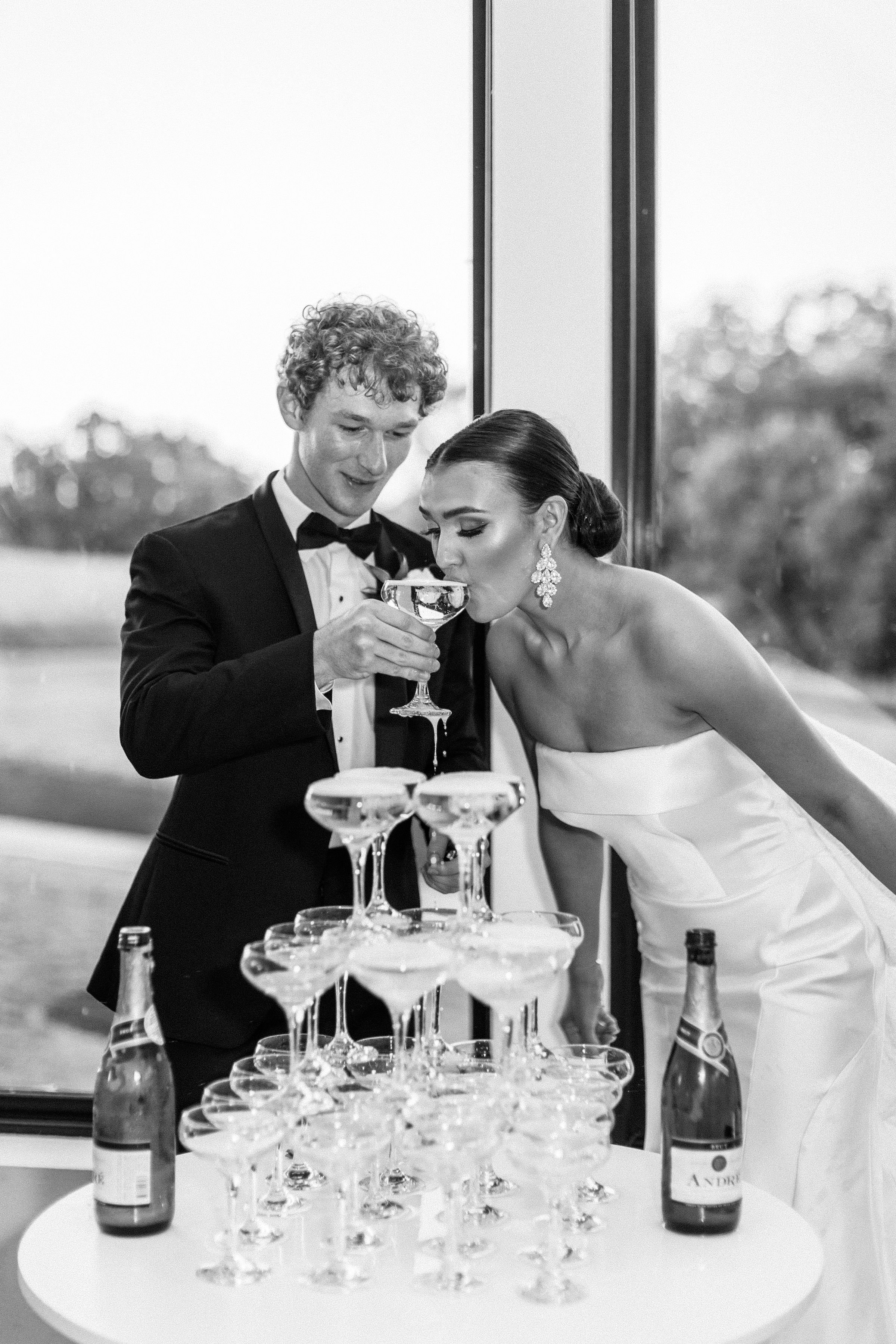 a bride sipping from a champagne tower at her modern and timeless wedding in a hera couture wedding gown