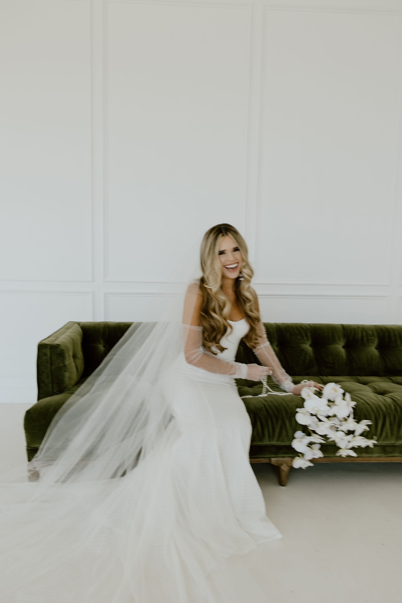 a classic bride wearing a dany tabet wedding dress on a green velvet couch.