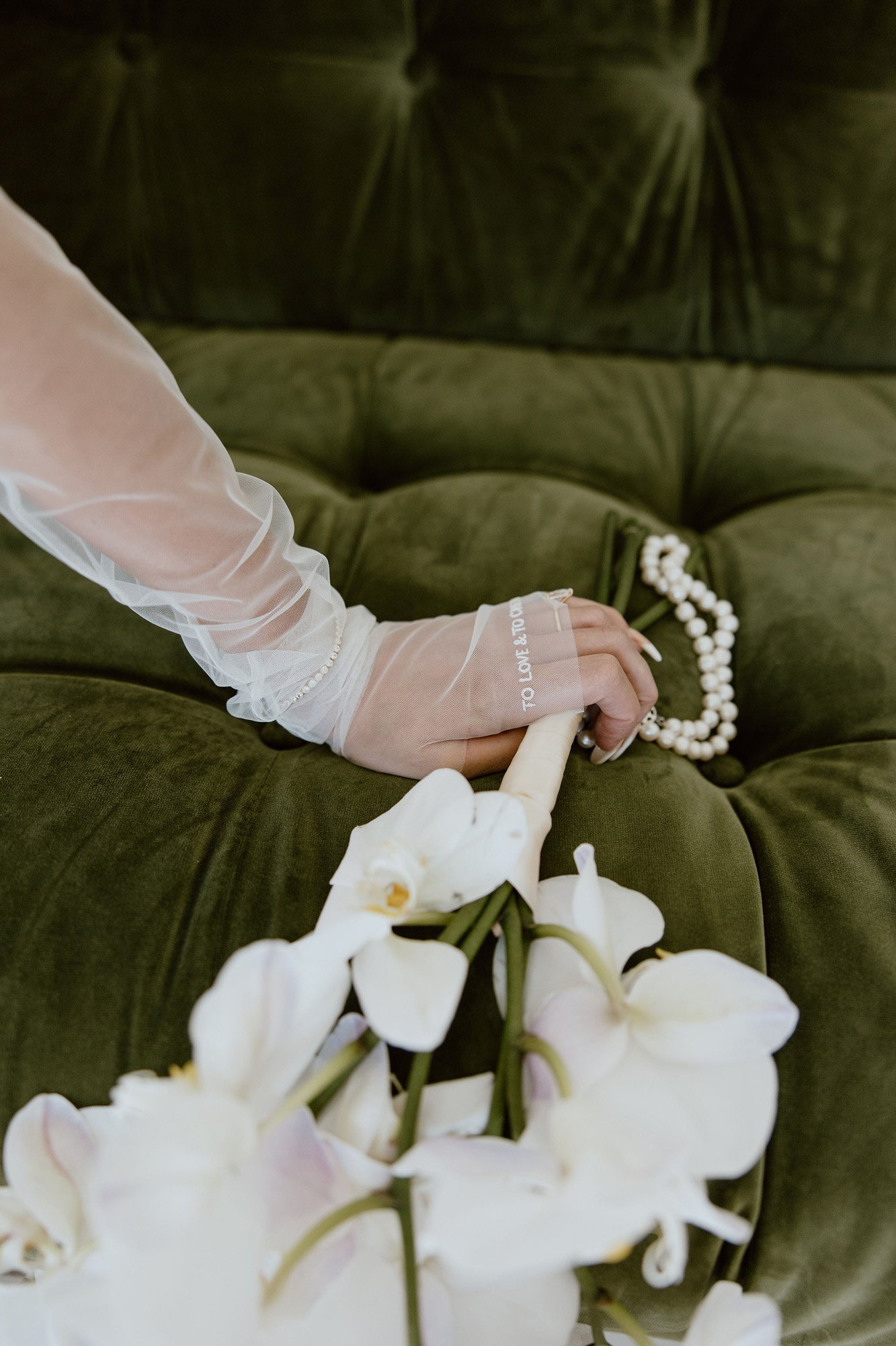 the brides white bouquet on a green velvet couch.