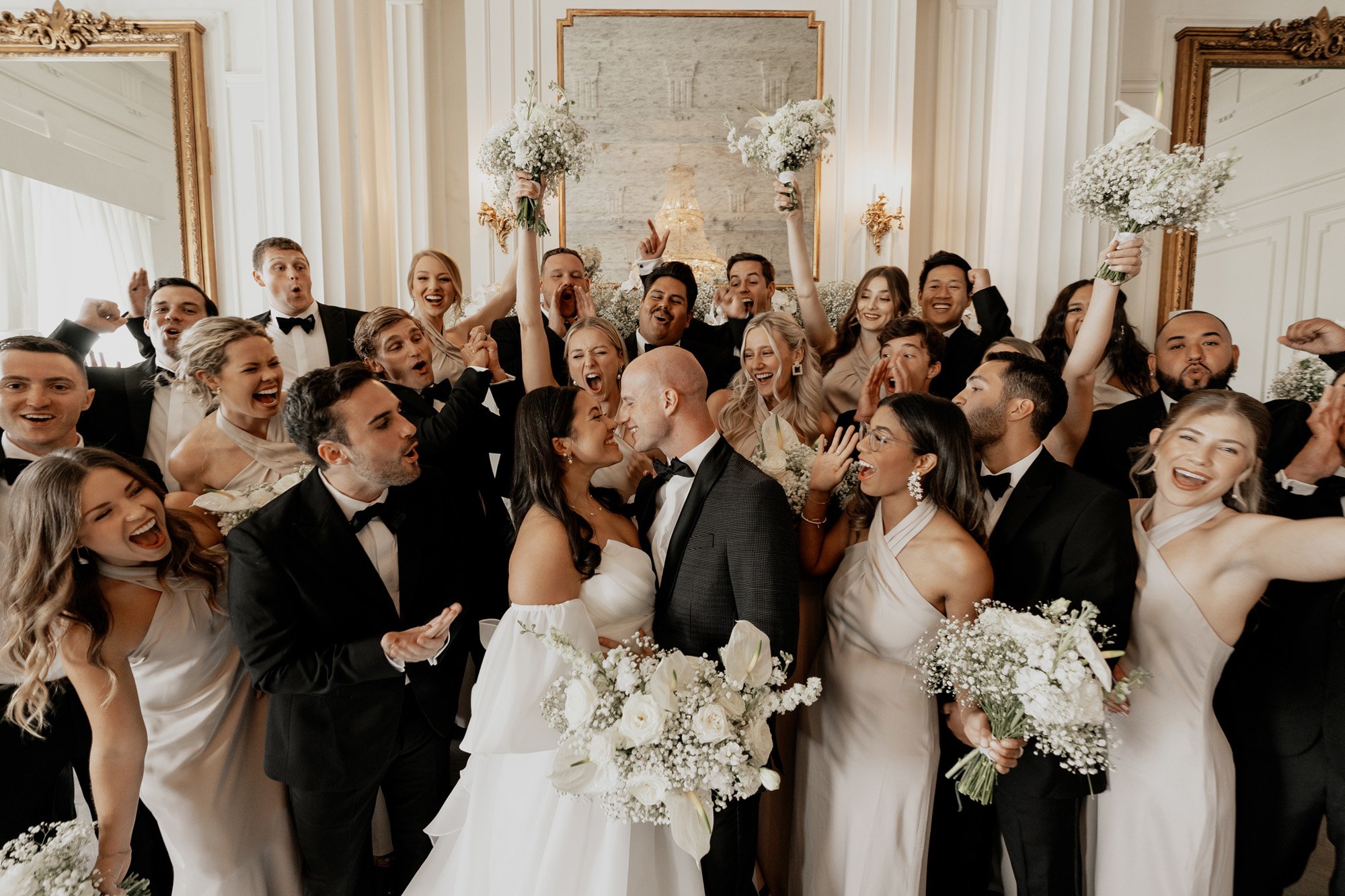 the modern wedding party photo with everyone cheering on the couple featuring a eva lendel ball gown from anna be 