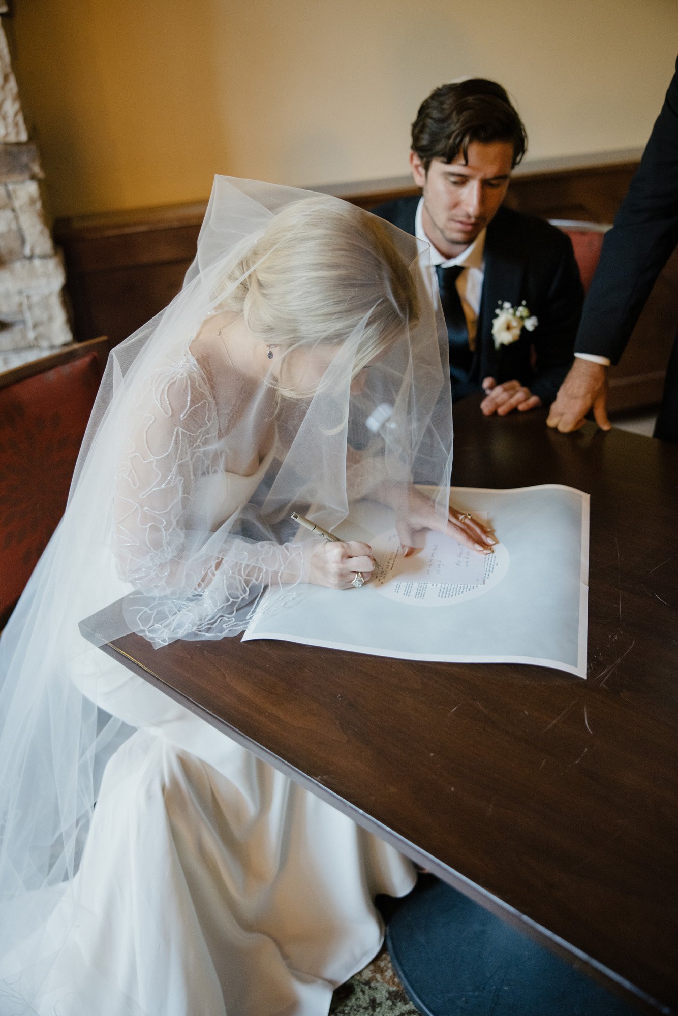 a modern jewish wedding ceremony as the bride and groom sign the ketuba before the ceremony featuring a anna be bridal boutique long sleeve wedding gown