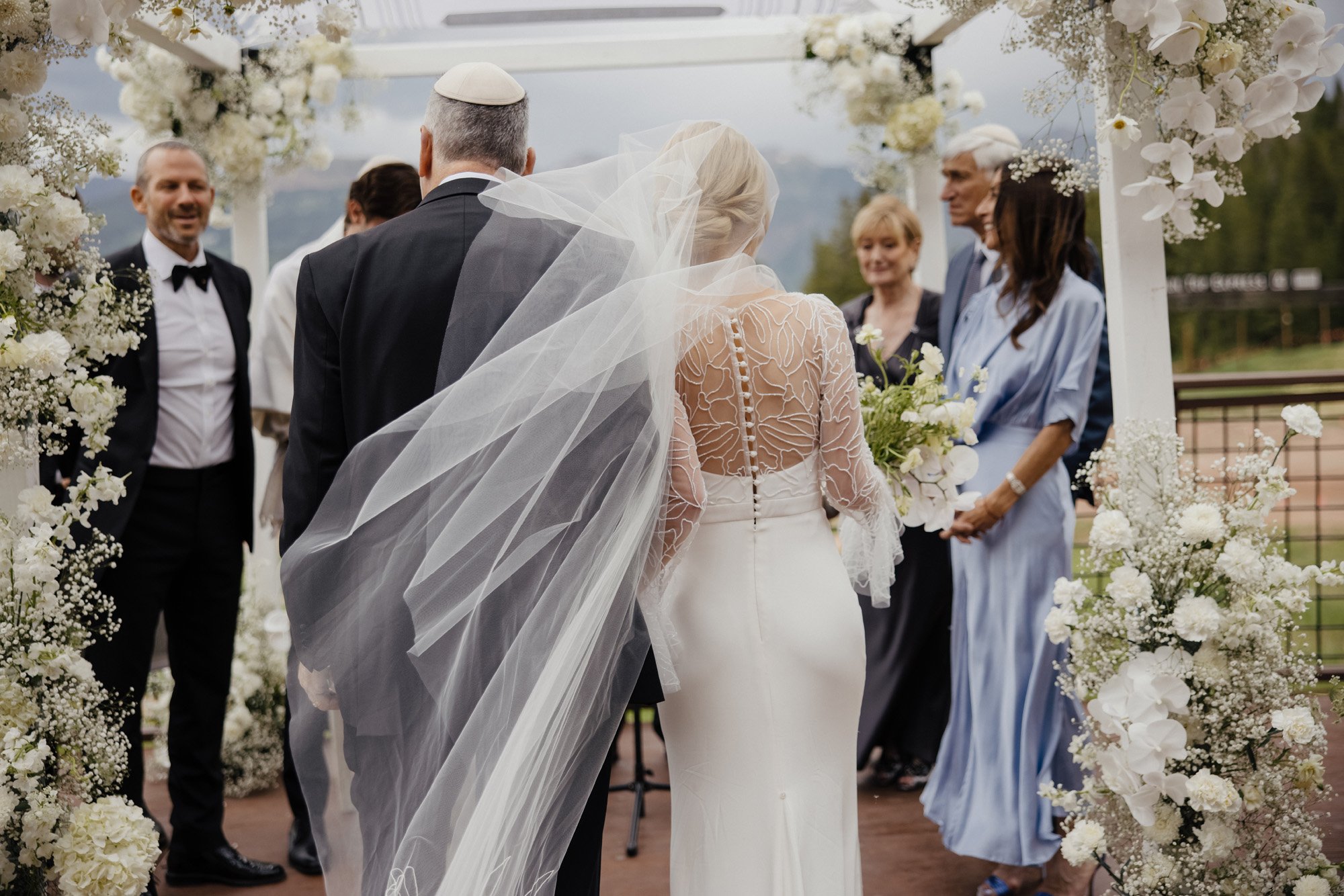 a modern jewish wedding ceremony under a chuppah featuring a long sleeve alexandra grecco wedding dress