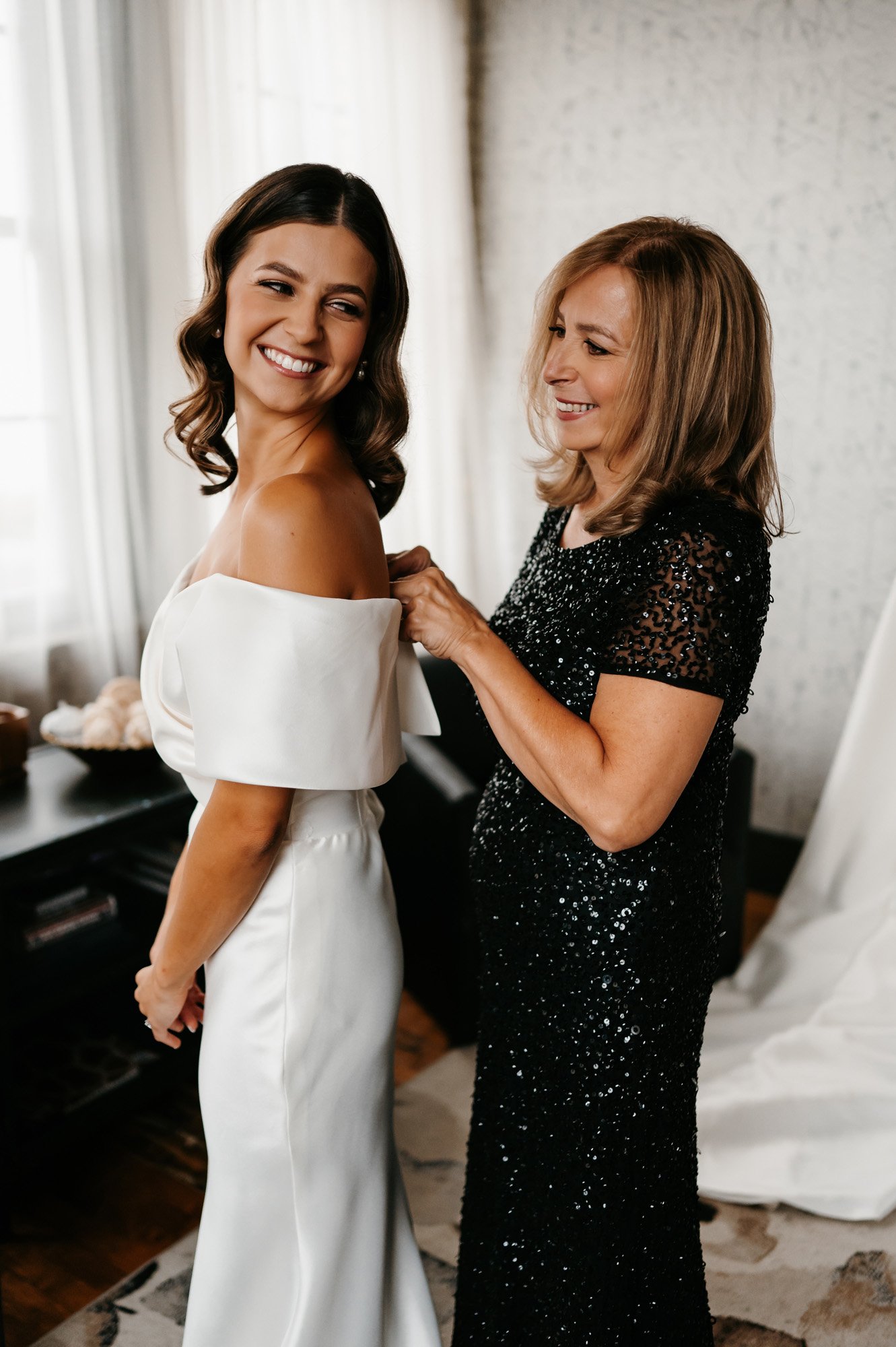 the bride and mother of the bride getting ready together in a modern white setting