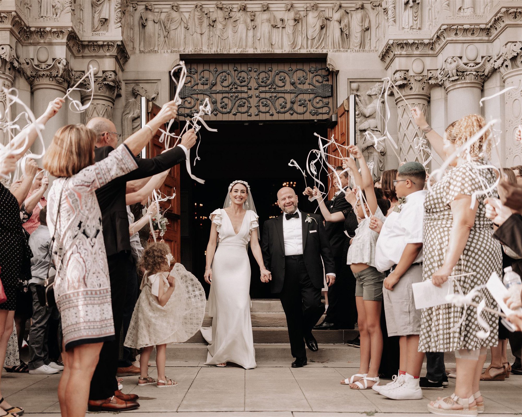 ribbon wedding exit outside this classic cathedral in st paul, minnesota featuring an alexandra grecco wedding dress from anna be bridal boutique.