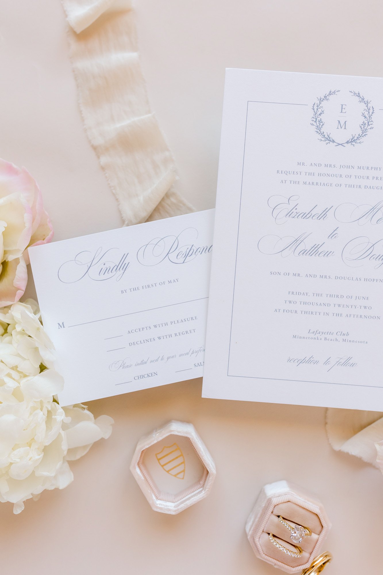  Traditional wedding invitations in white and blue with classic calligraphy surrounded by blush silk ribbons and rose petals 