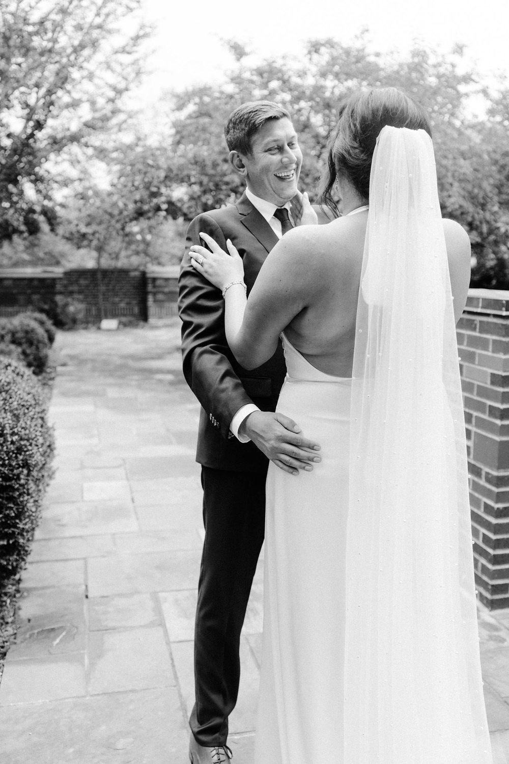  A bride and groom laughing and smiling while sharing an intimate first look before their wedding ceremony 