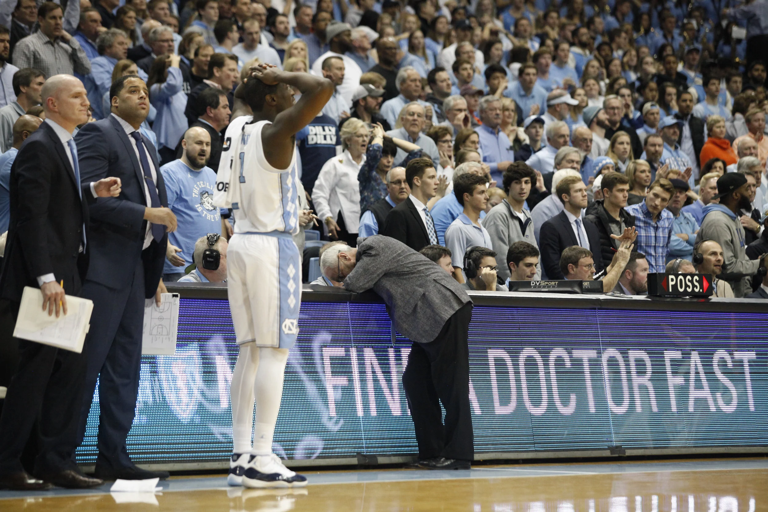 North Carolina coach Roy Williams leans on a table reading “Find A Doctor Fast” during the game against N.C. State at the Dean Smith Center.