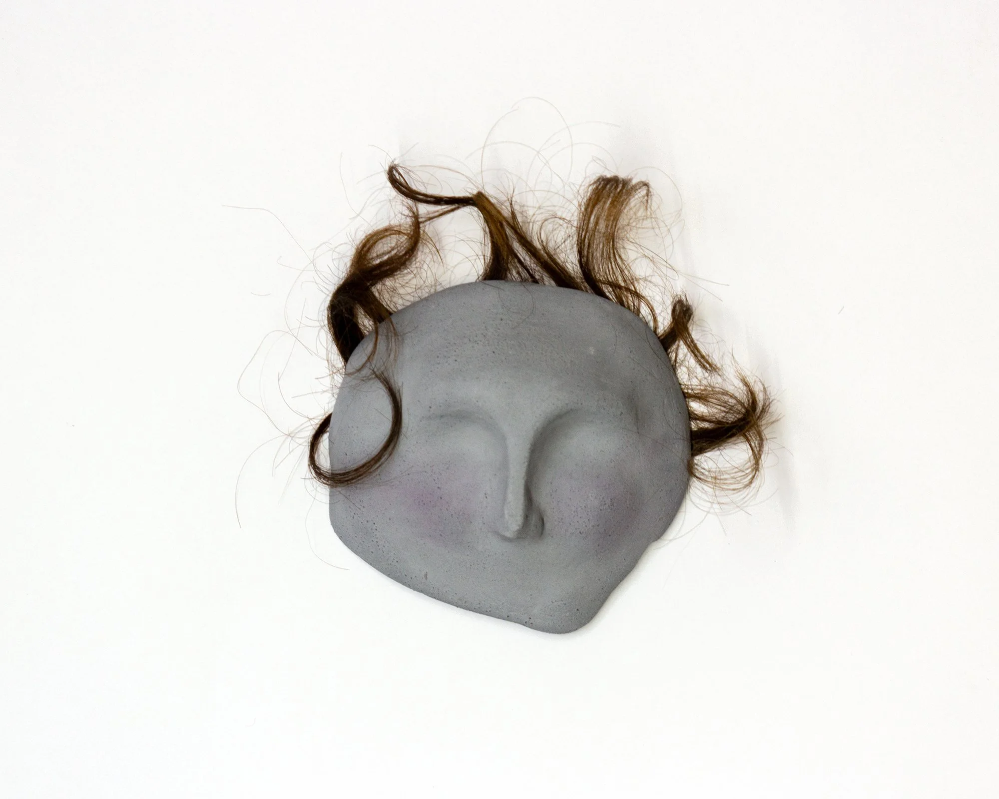 “Little face - mascaron”, 2025. Ceramic, human hair, 10 cm x 10 cm