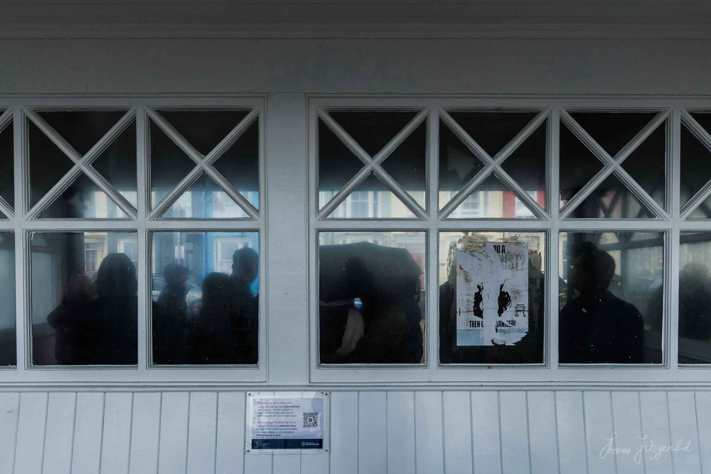 Tourists taking shelter in one of the promenade shelters on the Aberystwyth sea front a storm rolls across