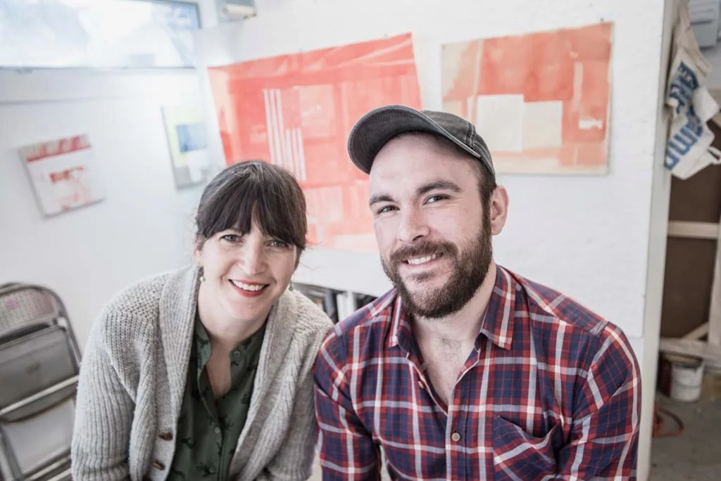 Jodi Hays and Matt Lovell in Jodi’s studio in front of original ink wash painting of the security footage of Matt getting shot. Photo Credit: Eric England