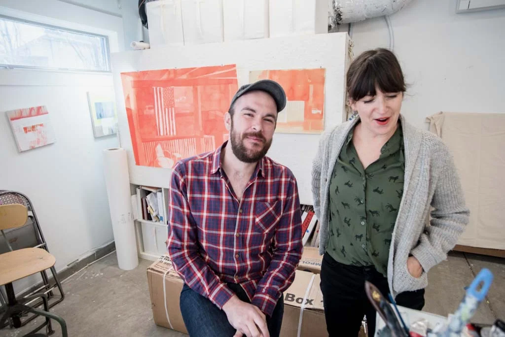 Jodi Hays and Matt Lovell in Jodi’s studio in front of original ink wash painting of the security footage of Matt getting shot. Photo Credit: Eric England