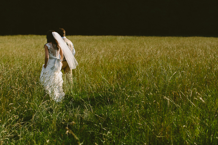 Bride and Groom Walking through Field