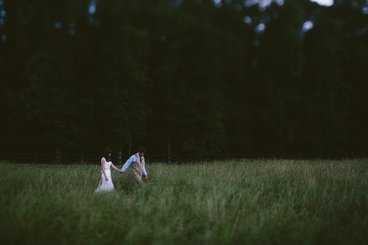 Bride and Groom Holding Hands Walking Through the Field